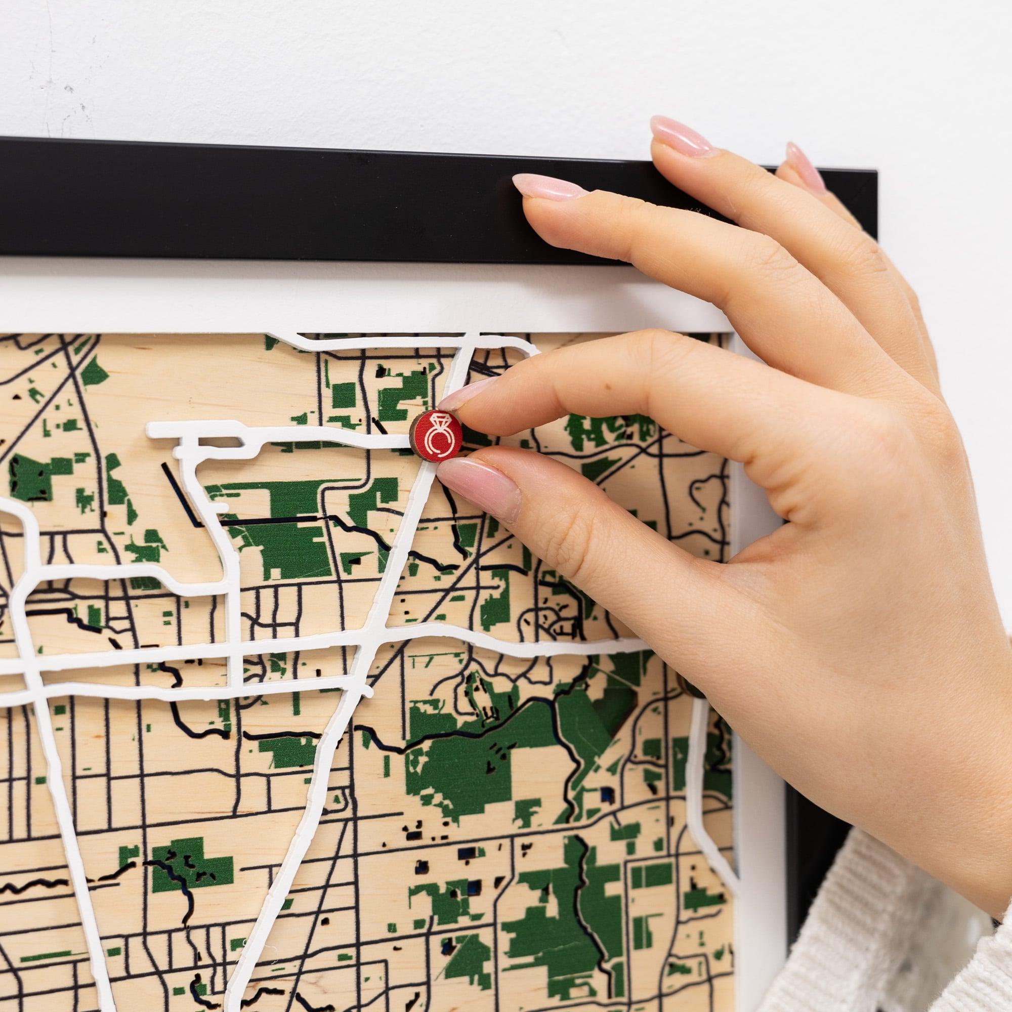 Hand placing a red pin on a map with a white background