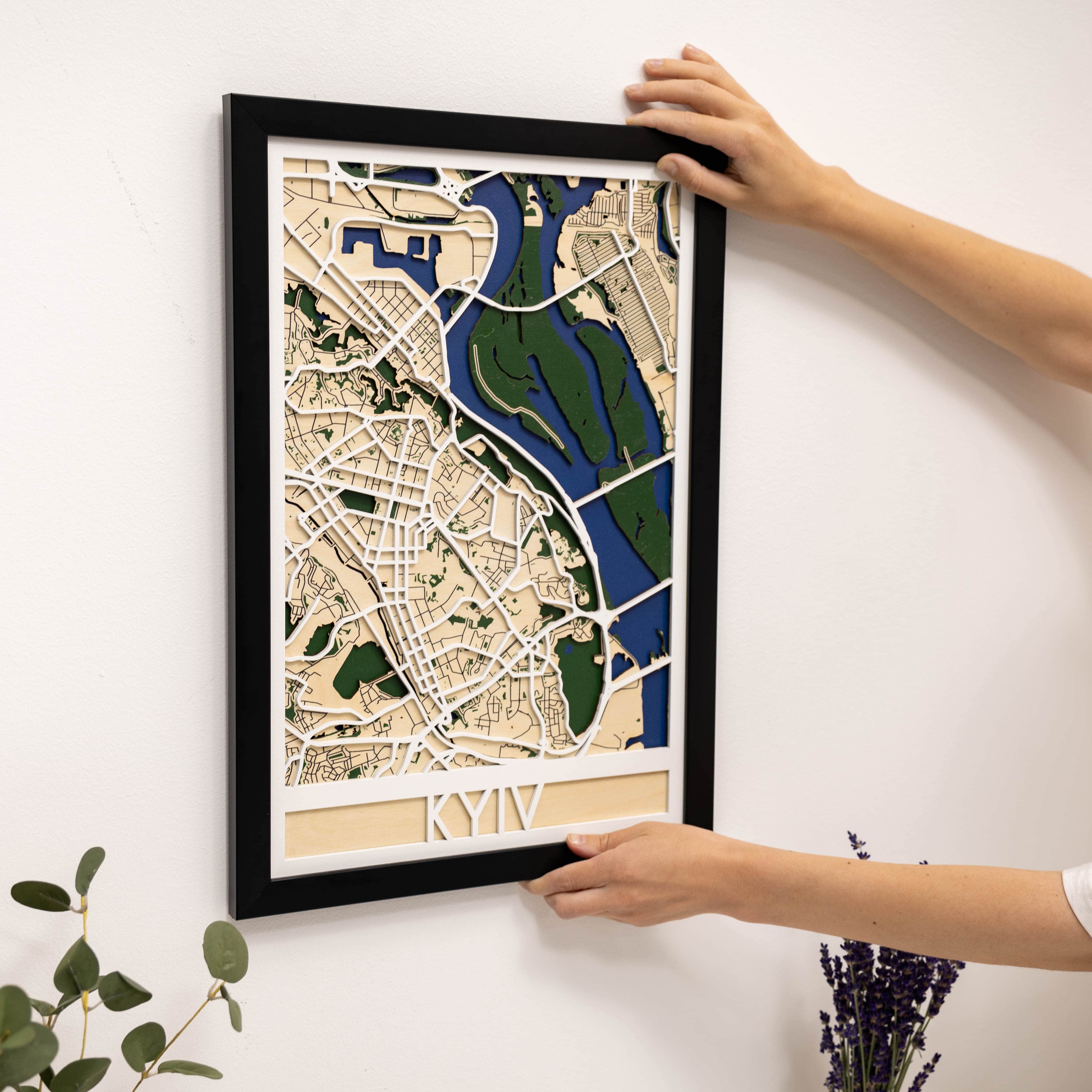 Framed city map being hung on a wall by a person