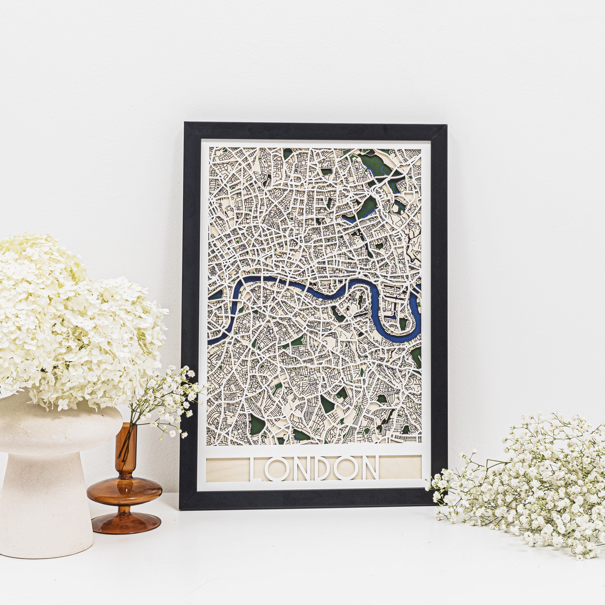 Framed map of London on a white surface with decorative flowers.