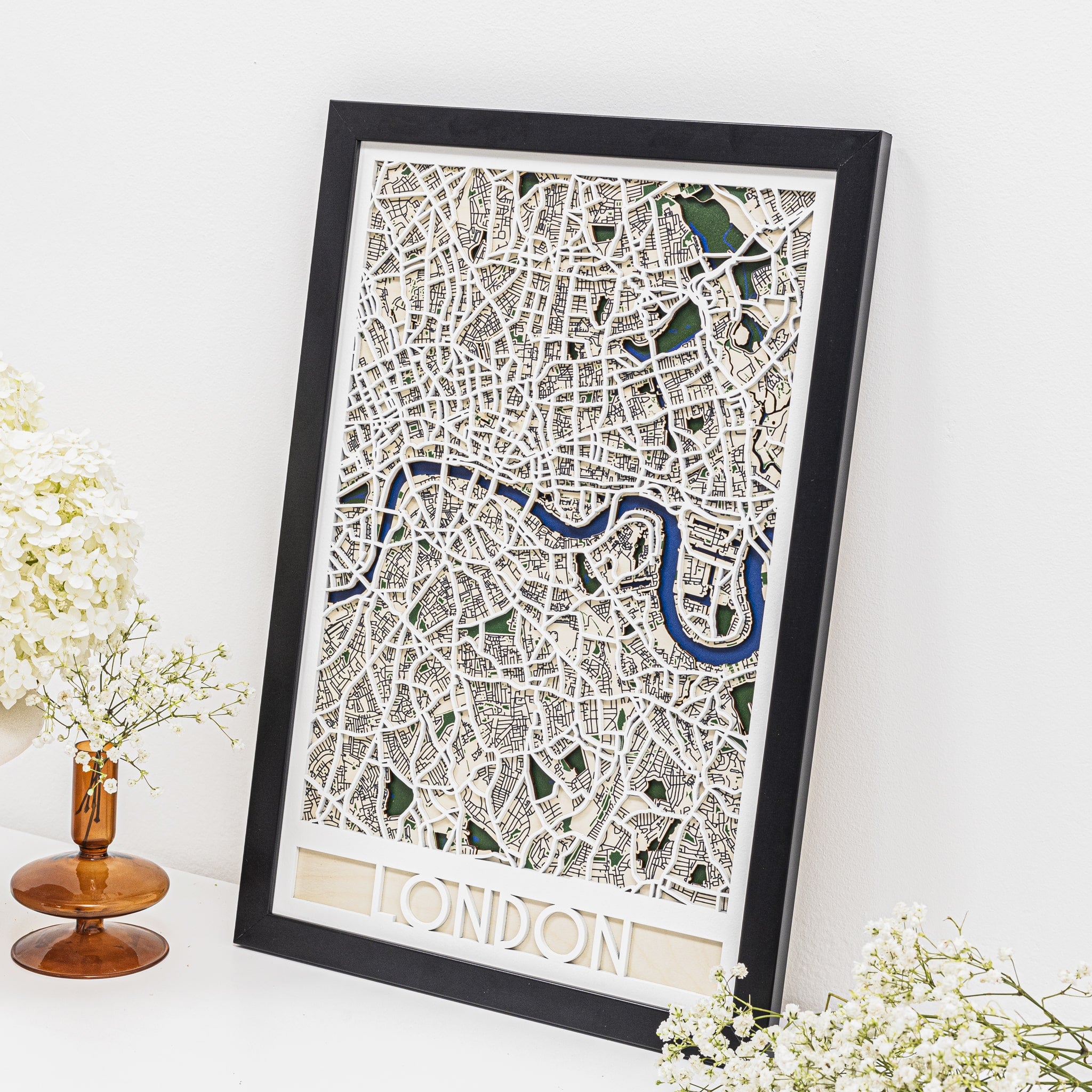 Framed map of London on a white surface with decorative flowers.