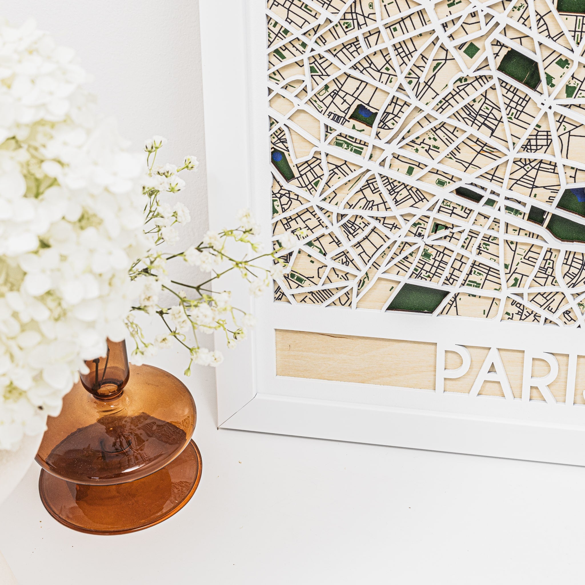 Decorative item with a map of Paris and white flowers on a light surface