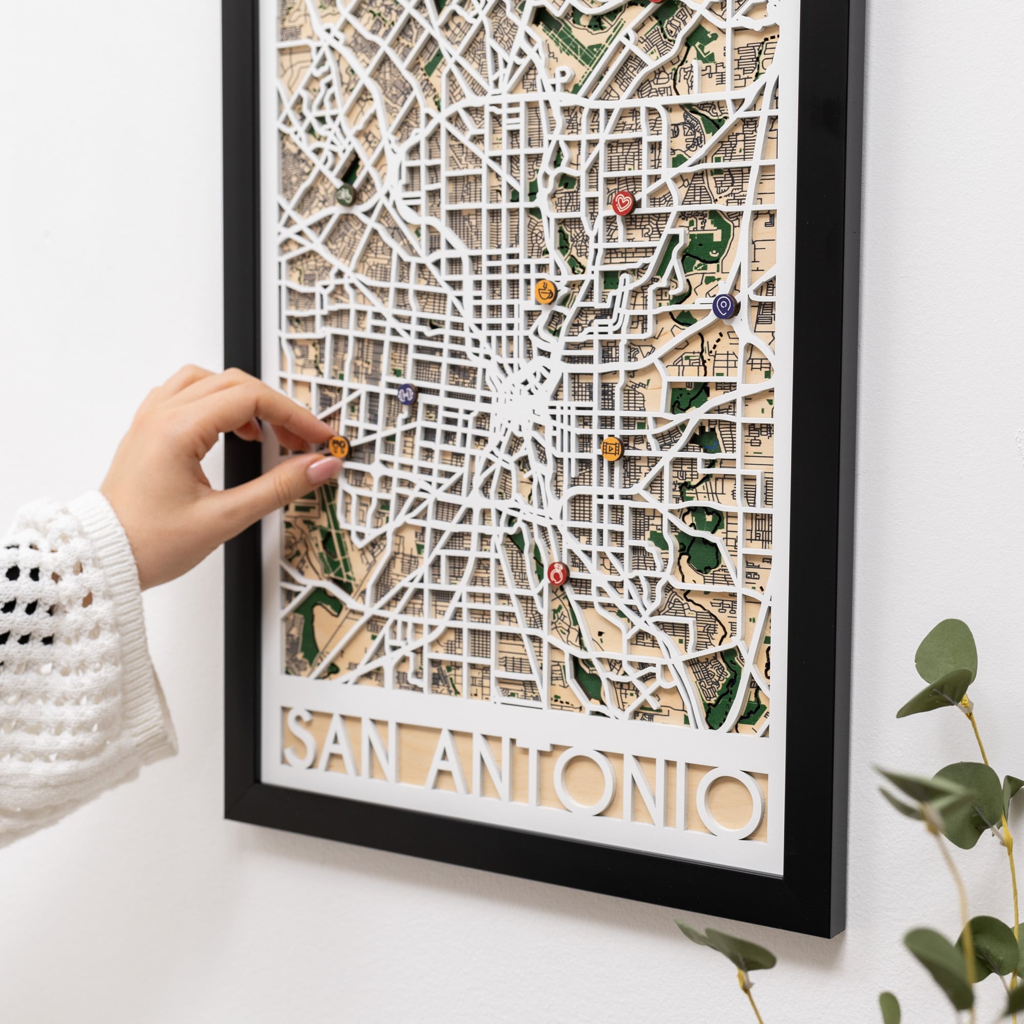 Framed map of San Antonio with decorative pins on a white surface.