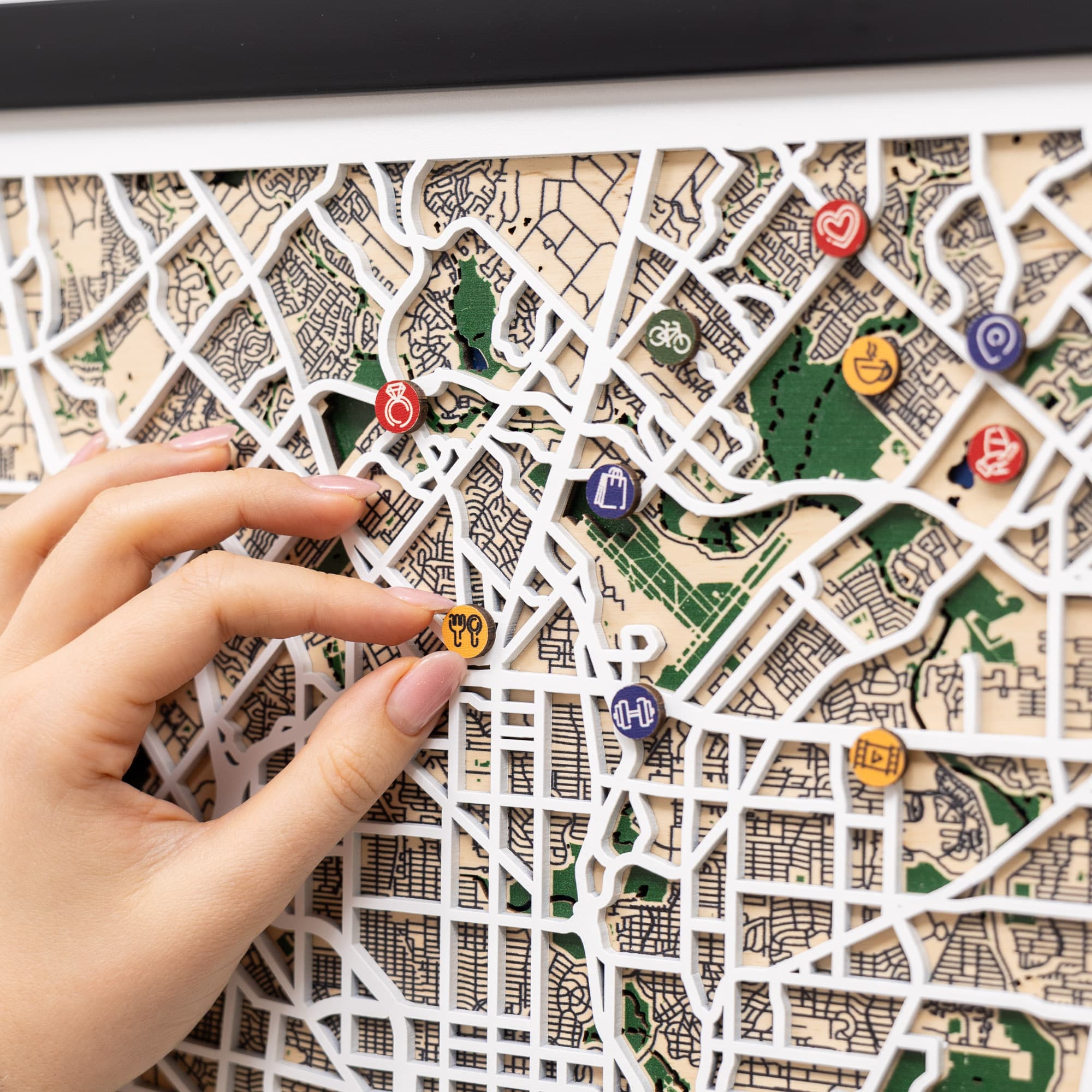 Framed map of San Antonio with decorative pins on a white surface.