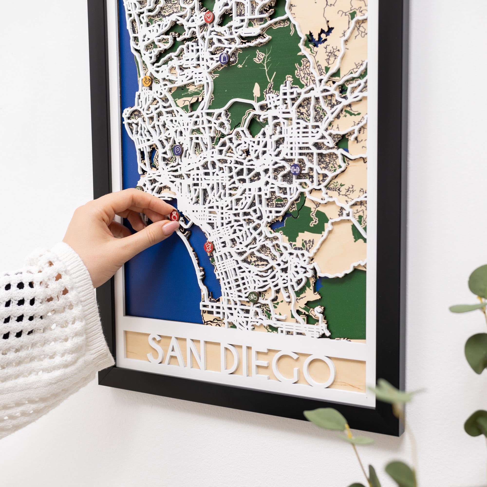 Framed 3D map of San Diego with a hand adjusting a piece.