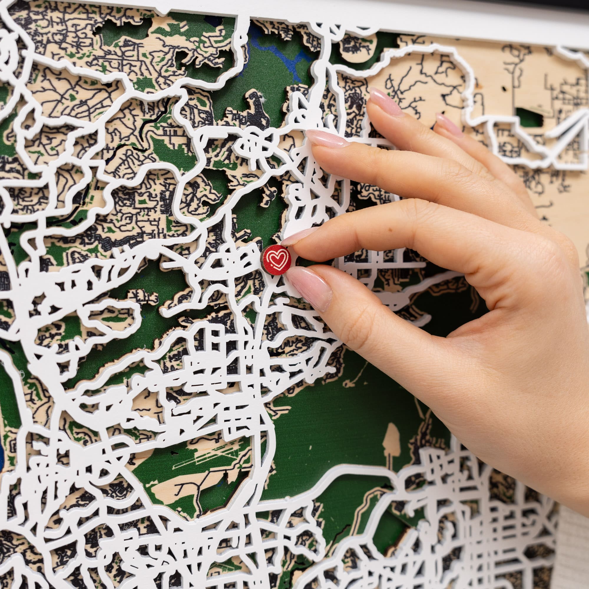 Hand placing a heart-shaped sticker on a map puzzle