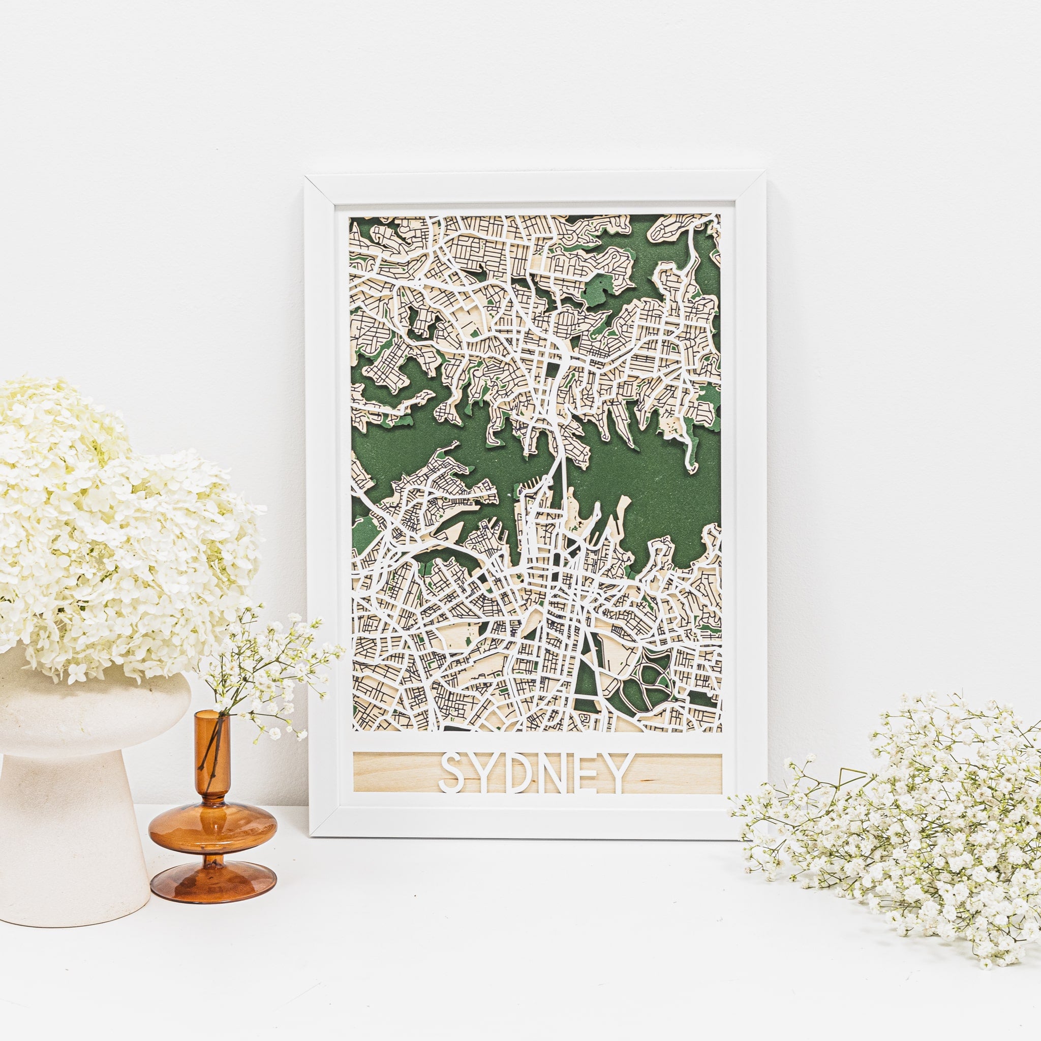 Framed map of Sydney on a white surface with decorative flowers.