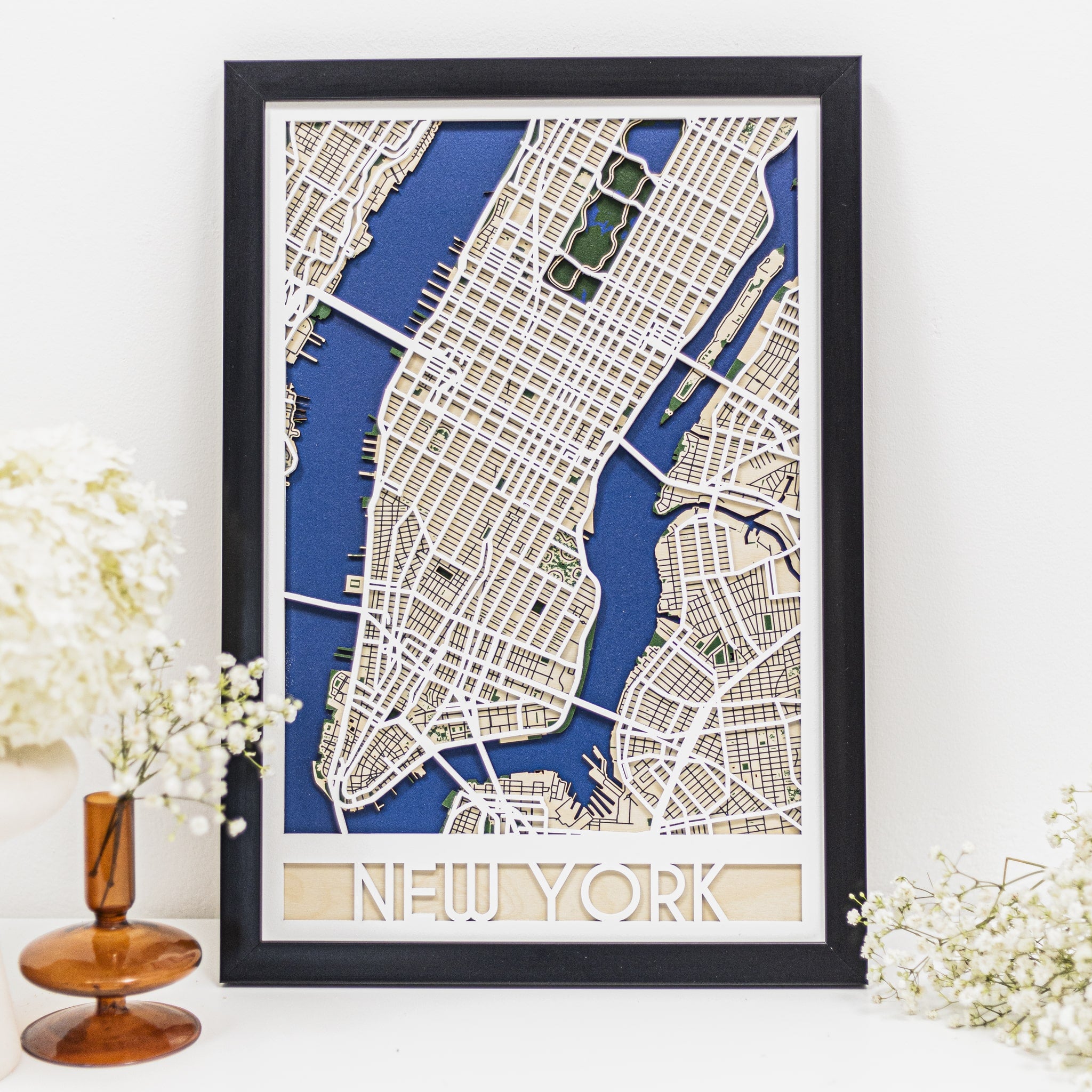 Framed map of New York on a white surface with decorative elements.