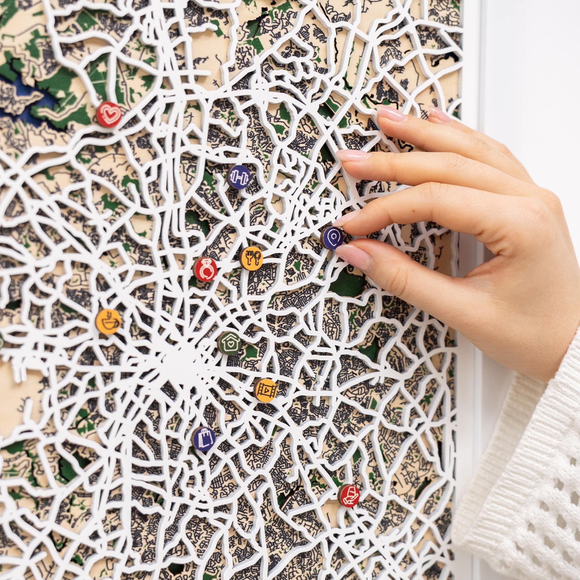 Hand placing colorful pins on a detailed map with a white lattice pattern
