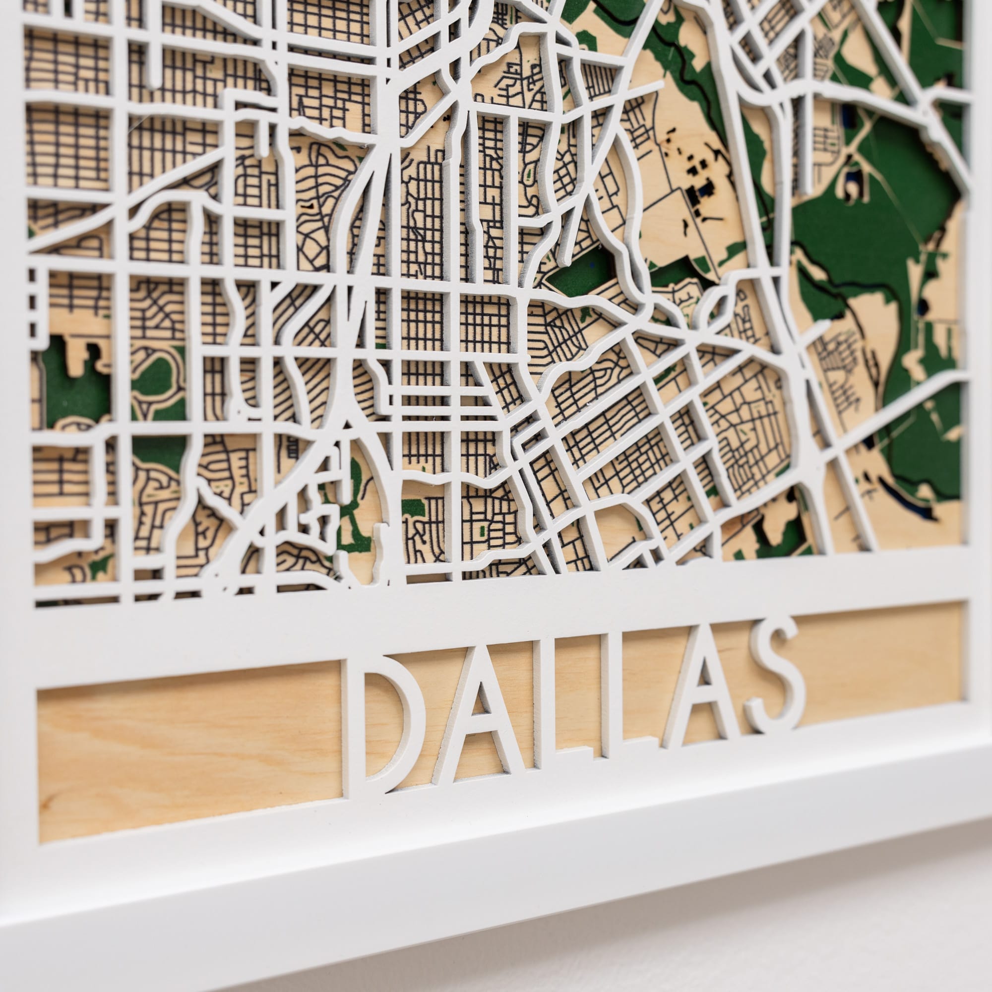 Wooden map of Dallas with cut-out street details and 'Dallas' text.