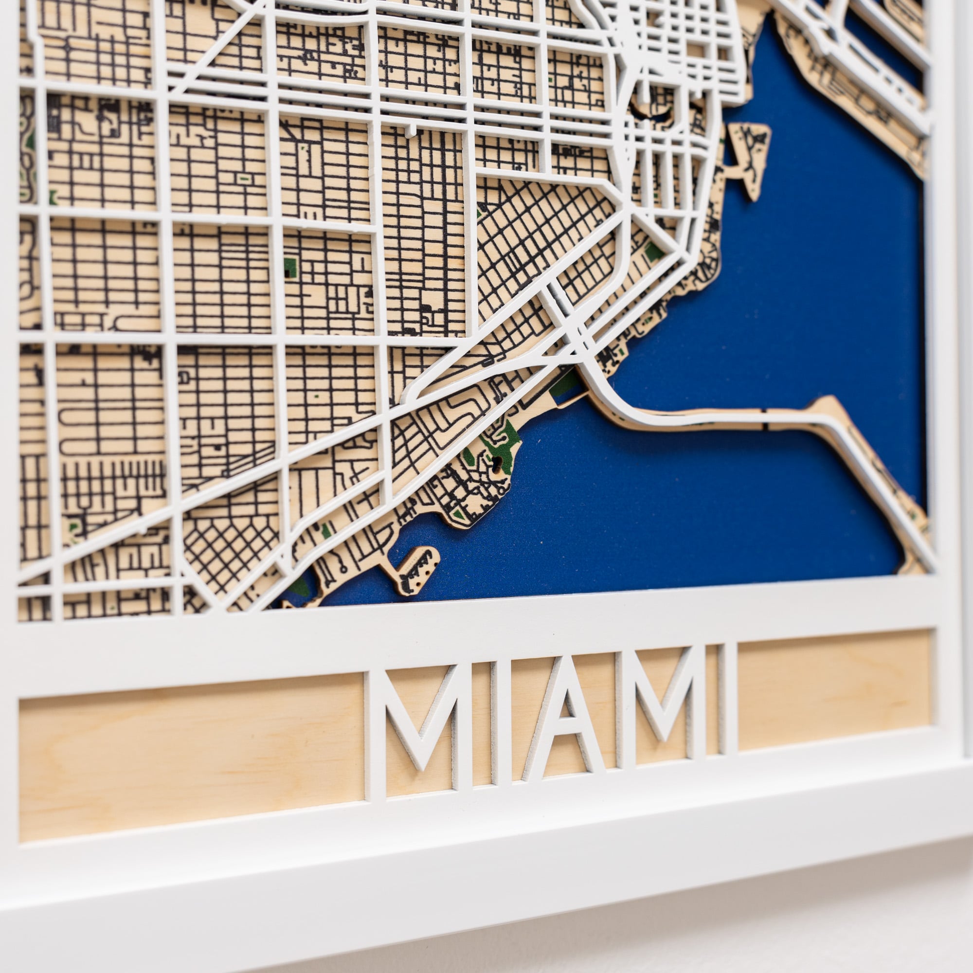 Wooden model of Miami's city layout with 'MIAMI' text on a white background