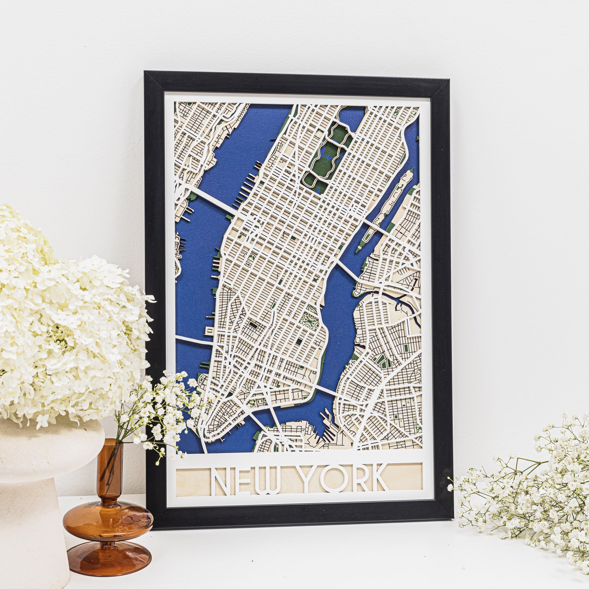 Framed map of New York City on a white wall with decorative elements.