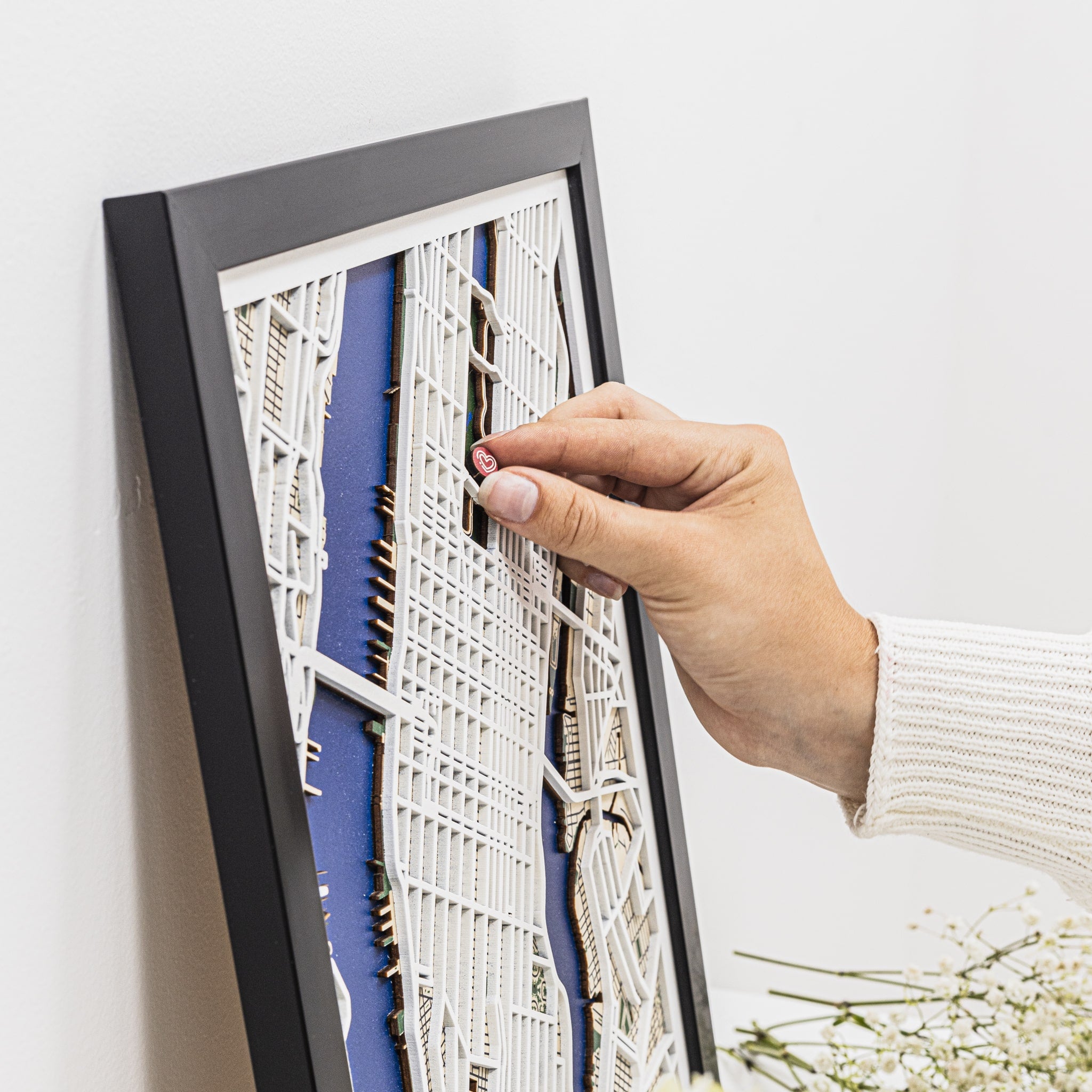 Hand adjusting a framed architectural model against a white wall