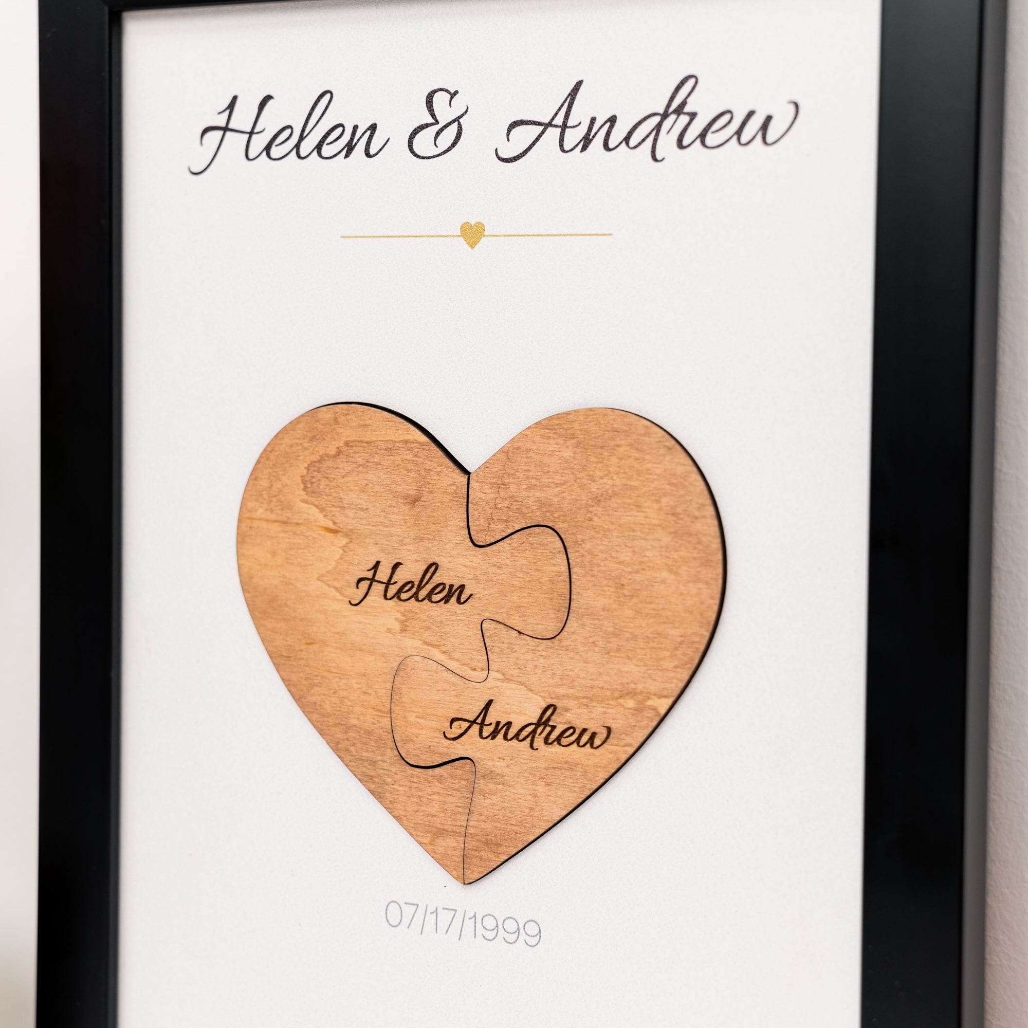 Wooden heart puzzle piece with engraved names and date, framed in black