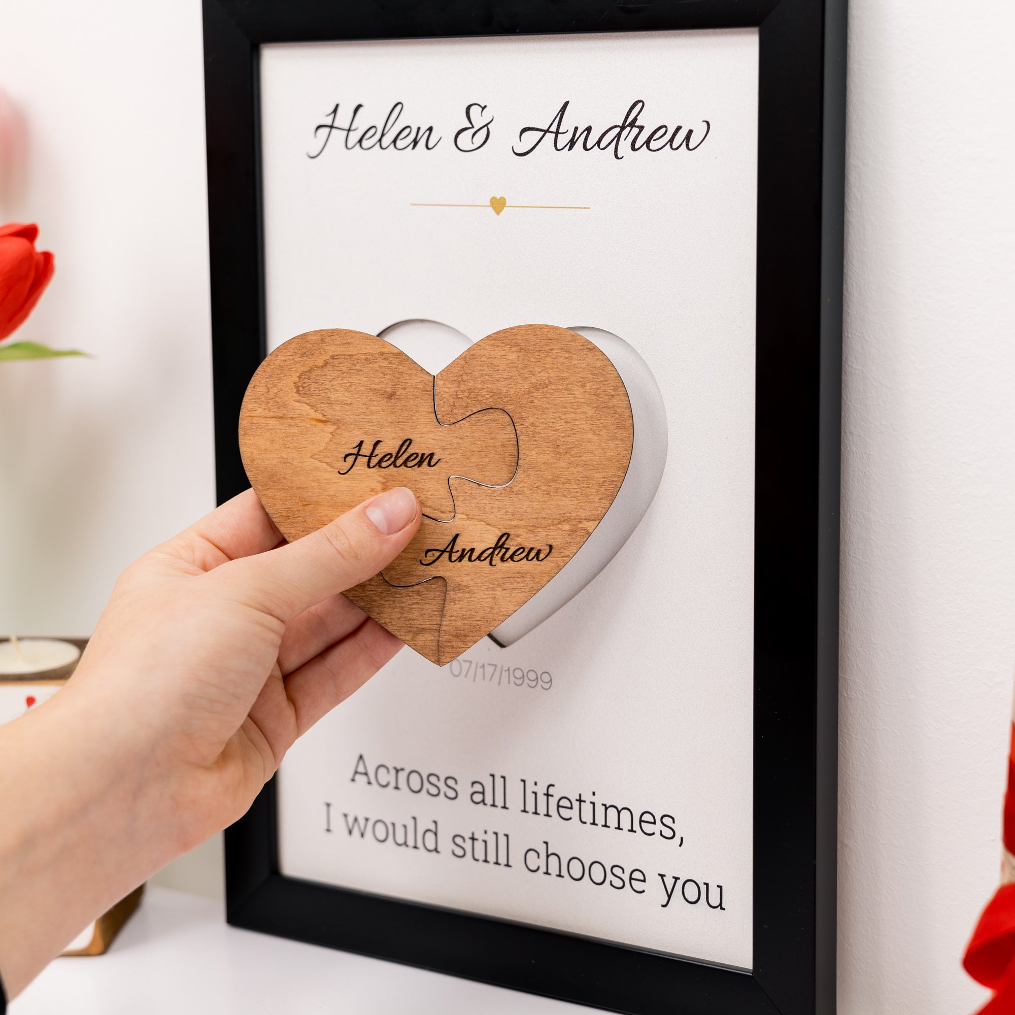 Wooden heart puzzle with engraved names in front of a framed quote