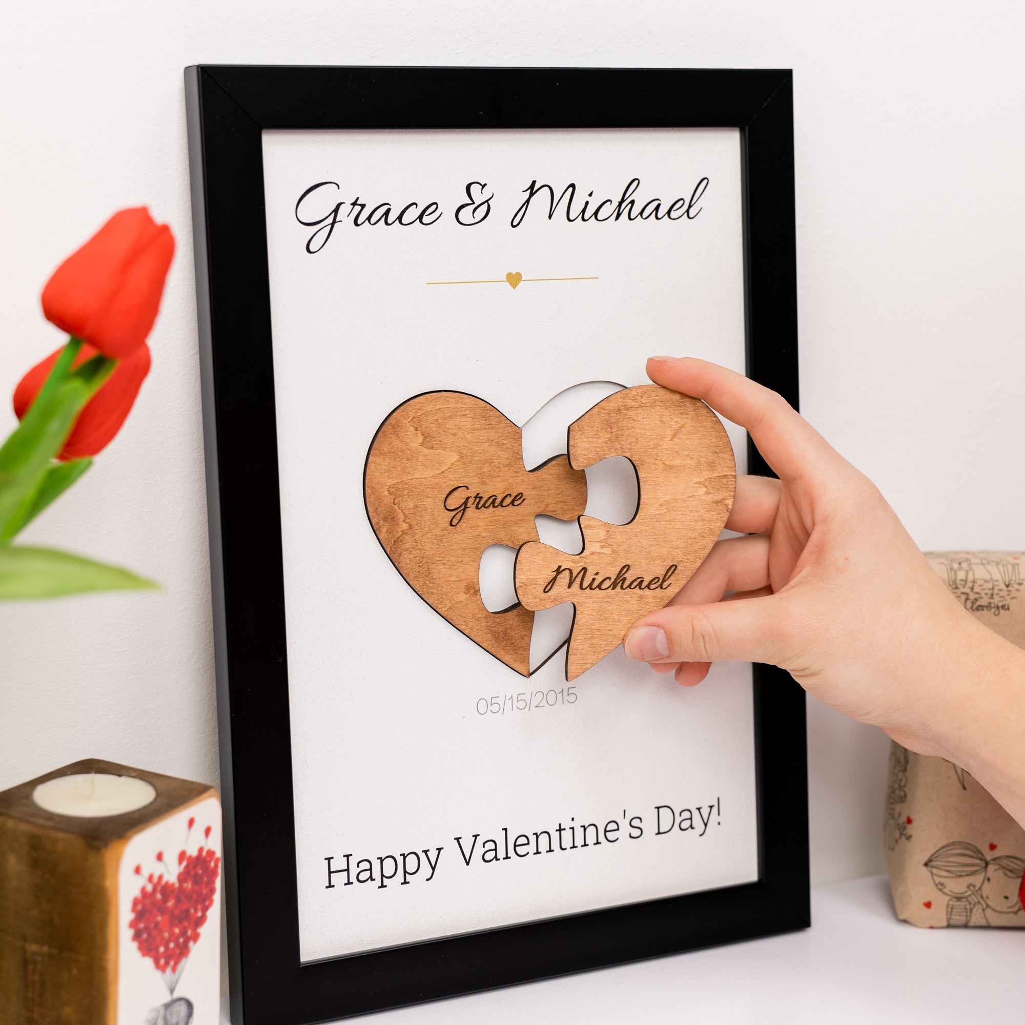 Heart-shaped puzzle piece with engraved names on a framed Valentine's Day card.