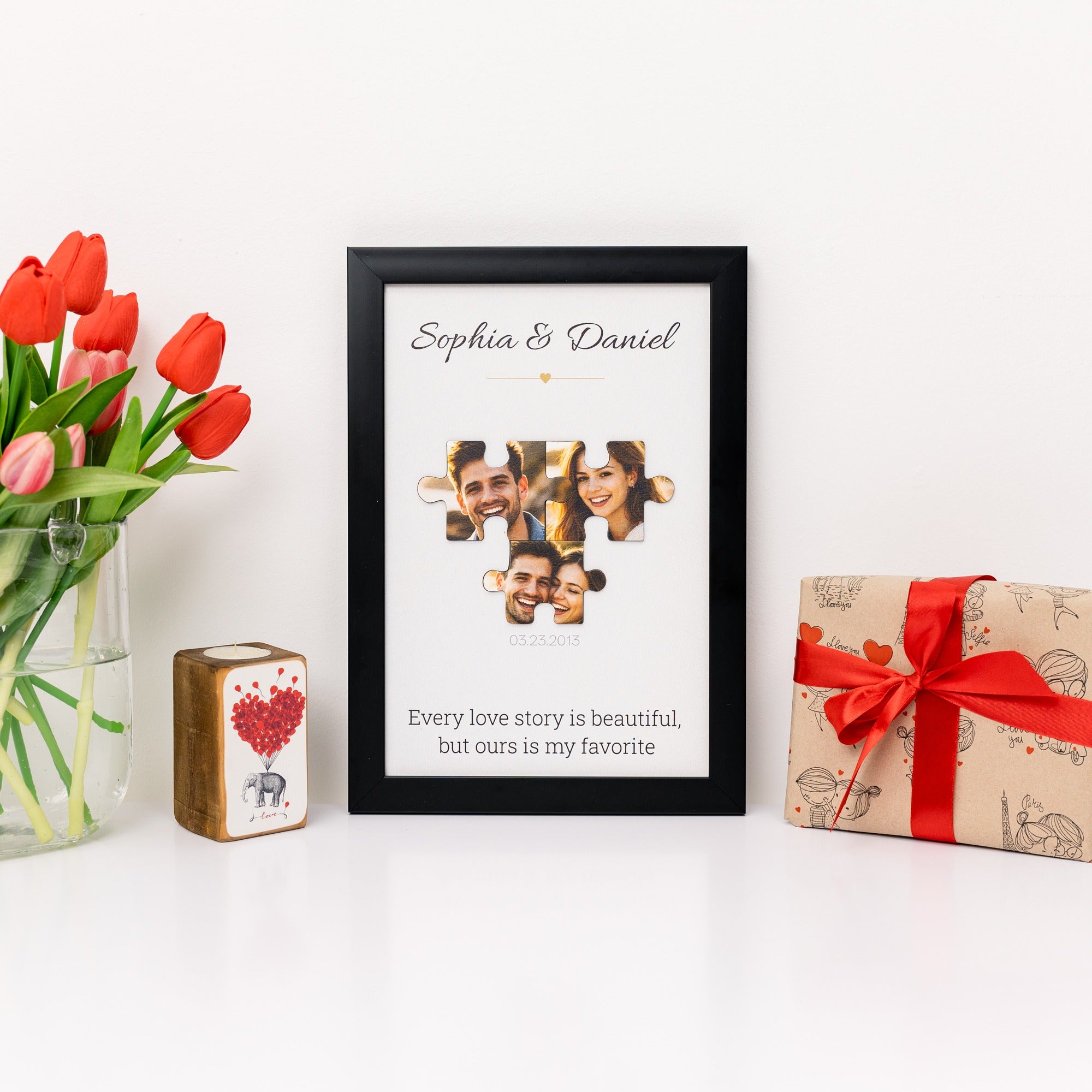 Personalized photo frame with a couple's collage and text, next to red tulips and a gift box on a white surface.