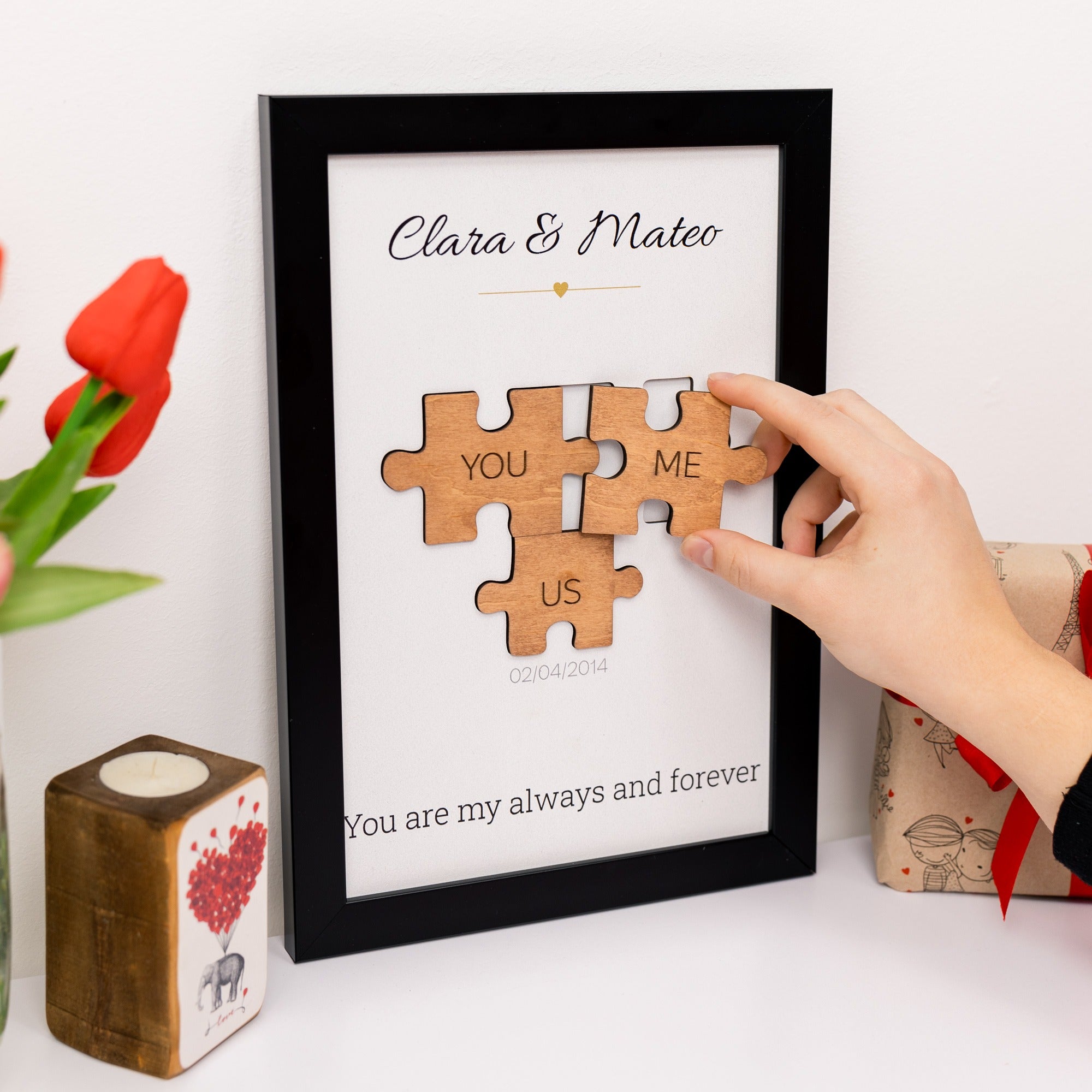 Wooden puzzle pieces with 'YOU', 'ME', and 'US' text in a framed picture, held by a hand.