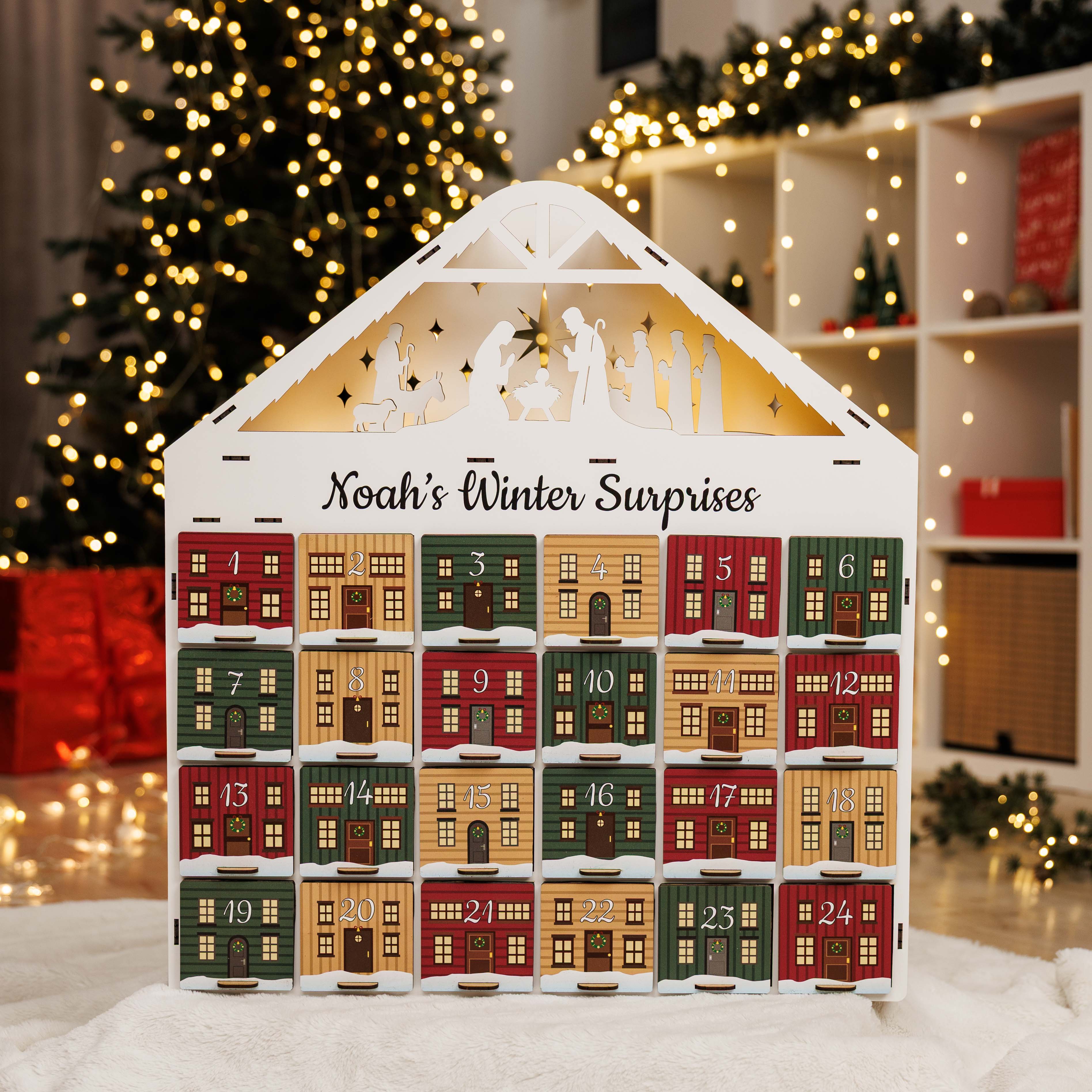 Advent calendar with house design in a festive setting with Christmas tree and lights.