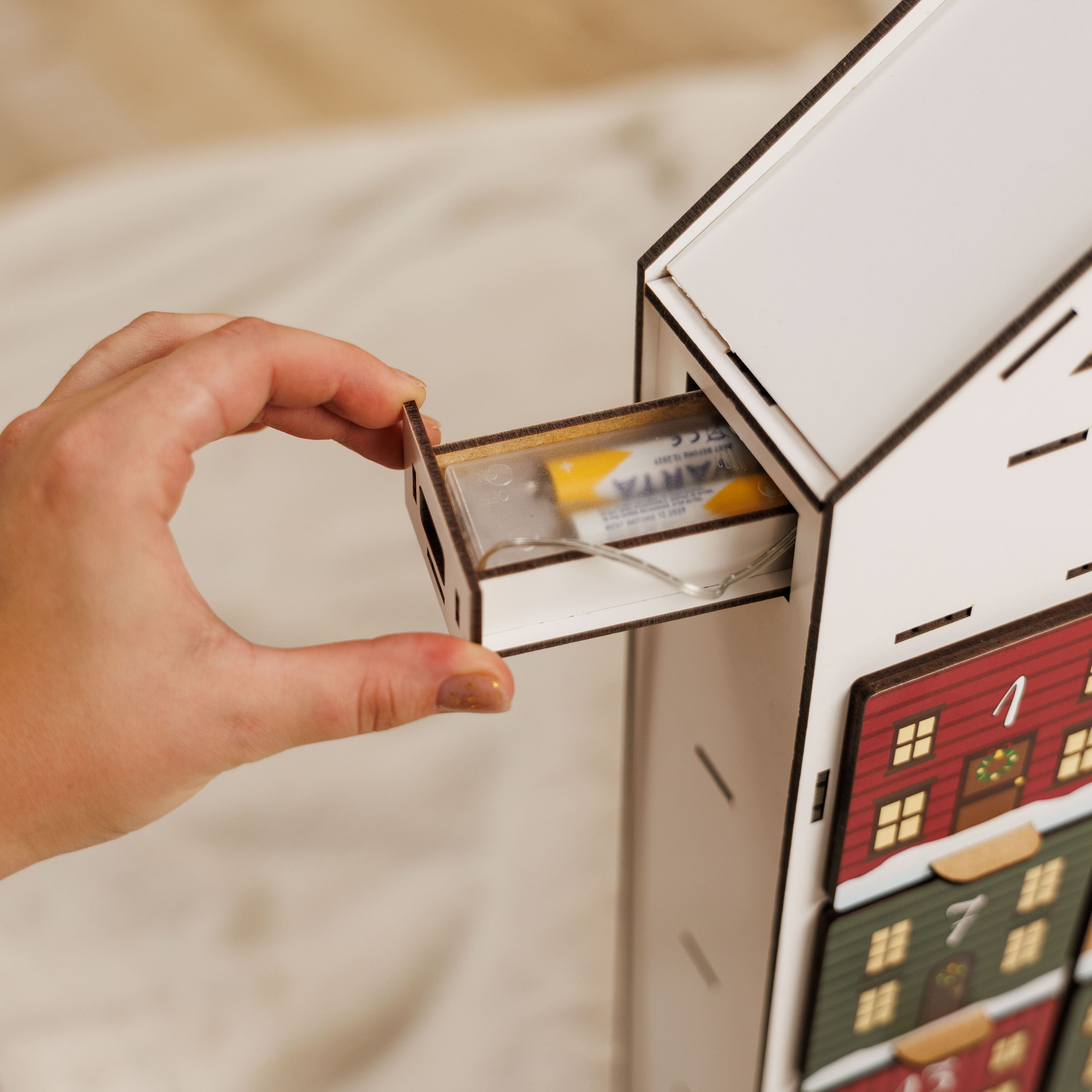 Hand opening a drawer in a miniature house model with a blurred background
