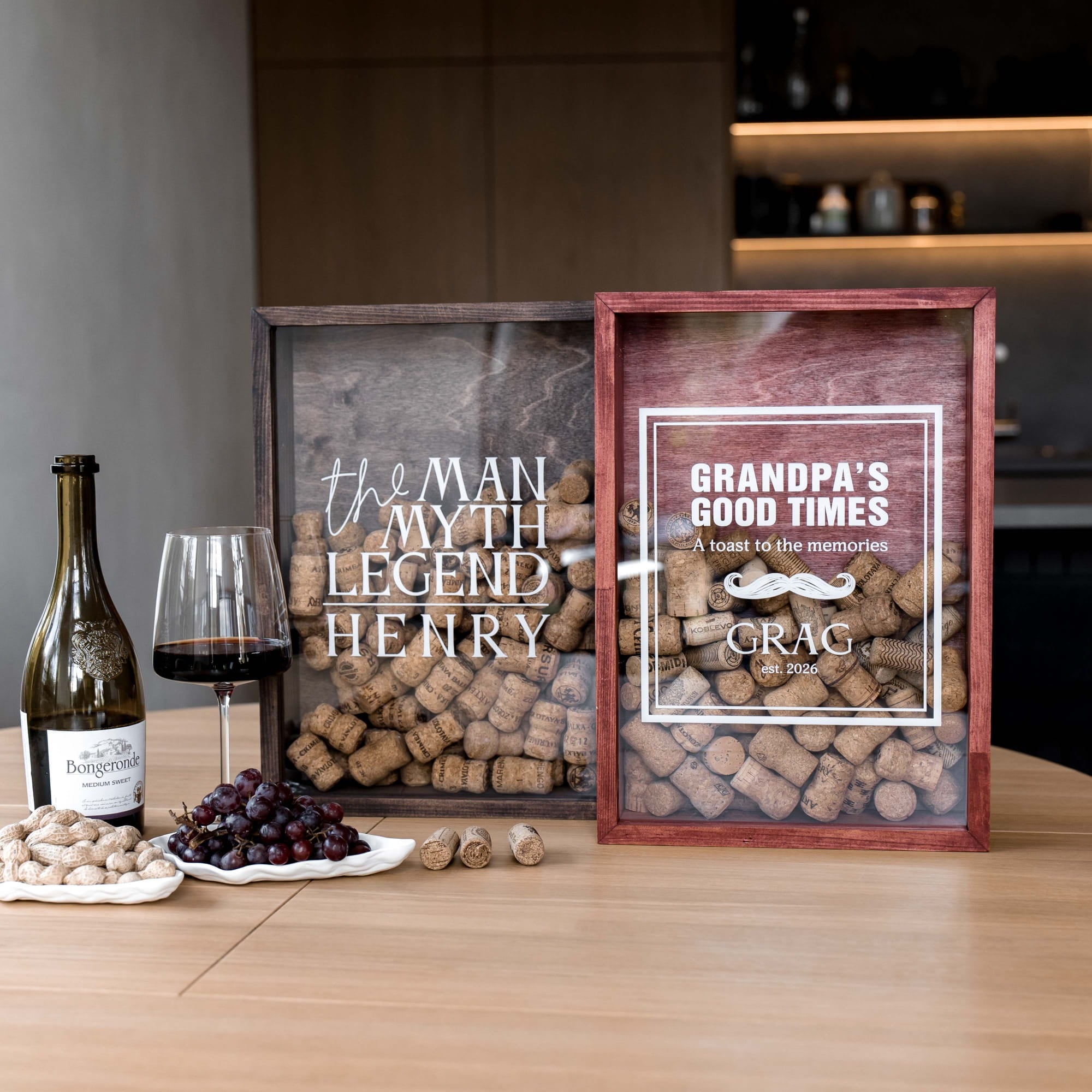Two personalized wooden wine cork shadow boxes on a wooden table