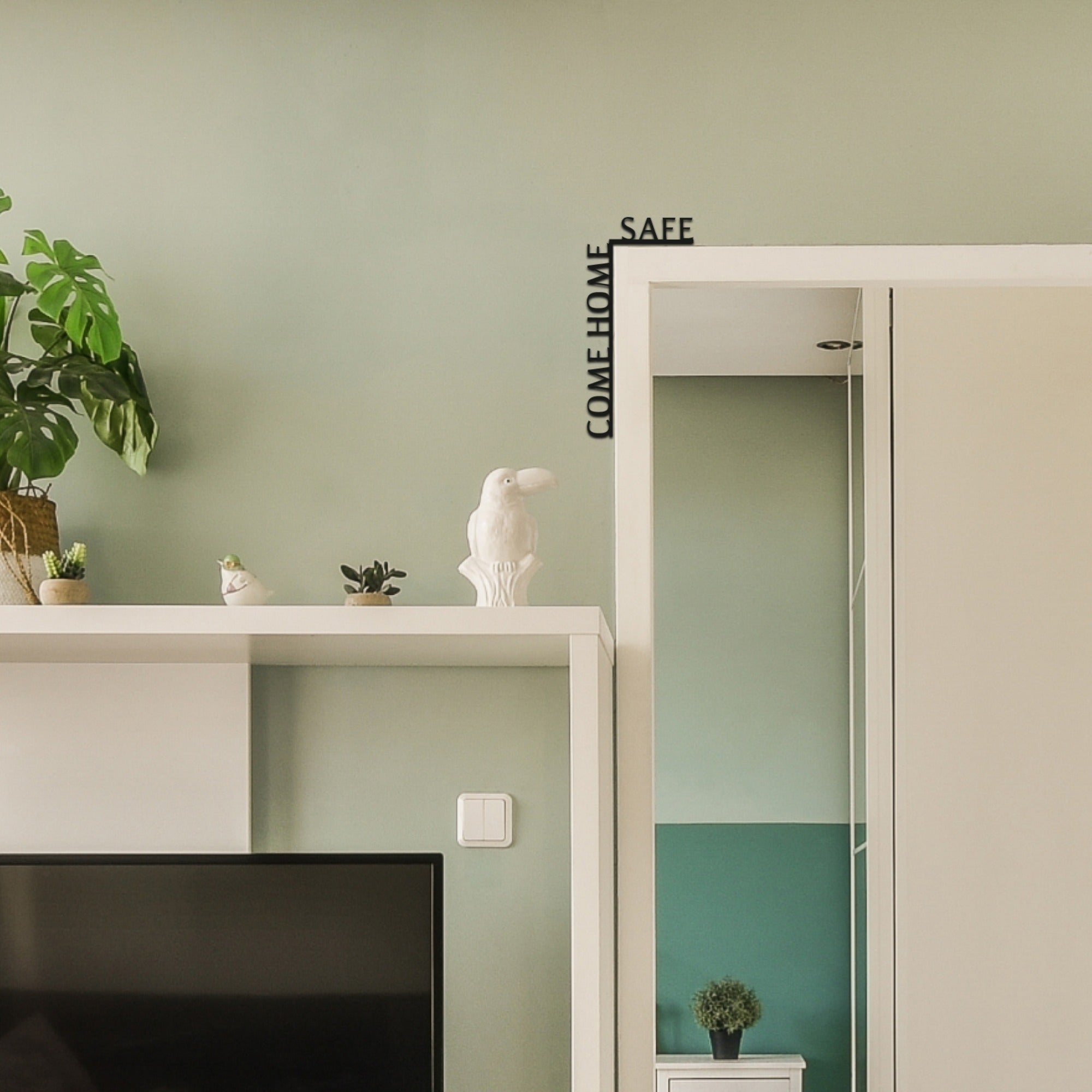 Decorative shelf with plants and a rabbit figurine against a light green wall.