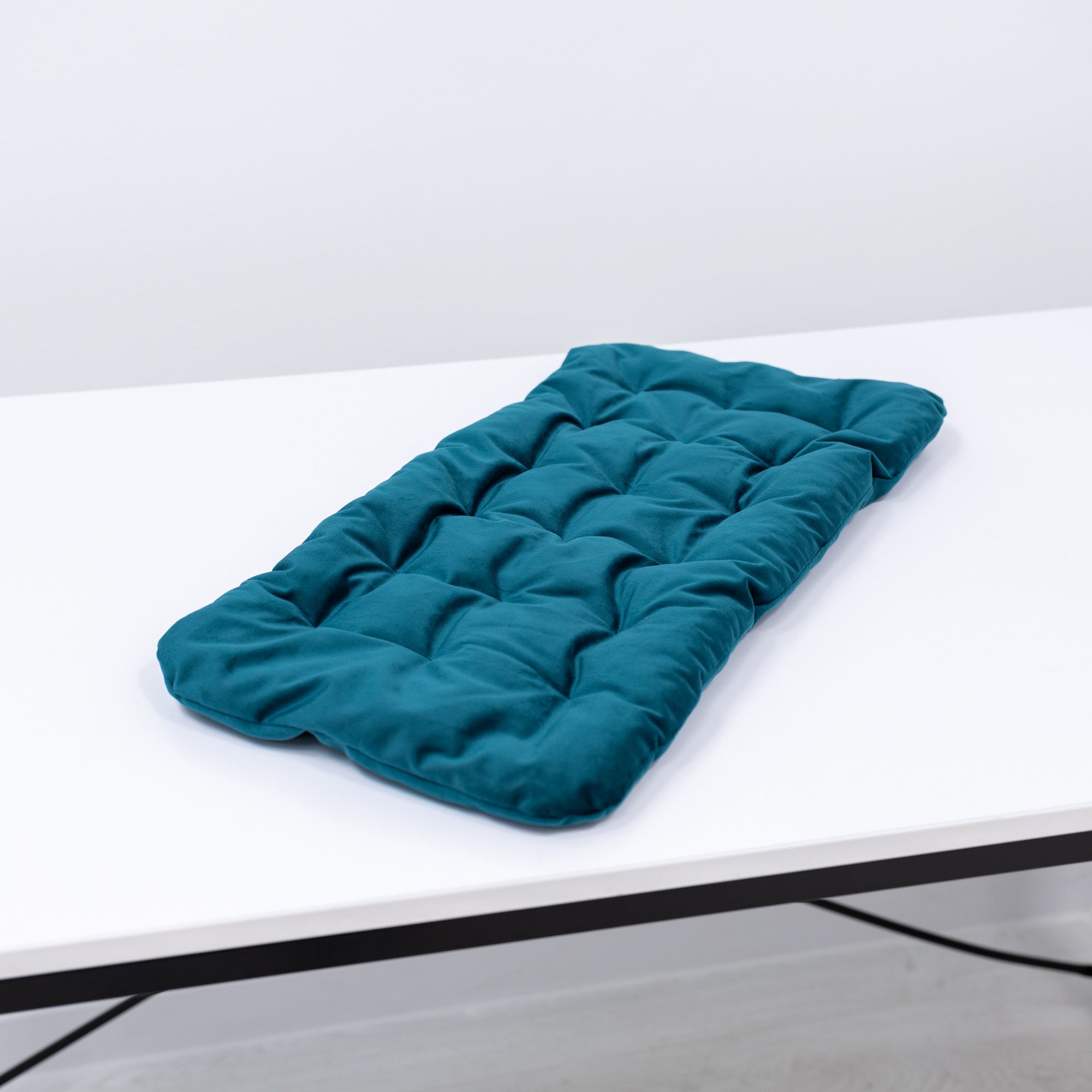 Teal quilted cover on a white surface