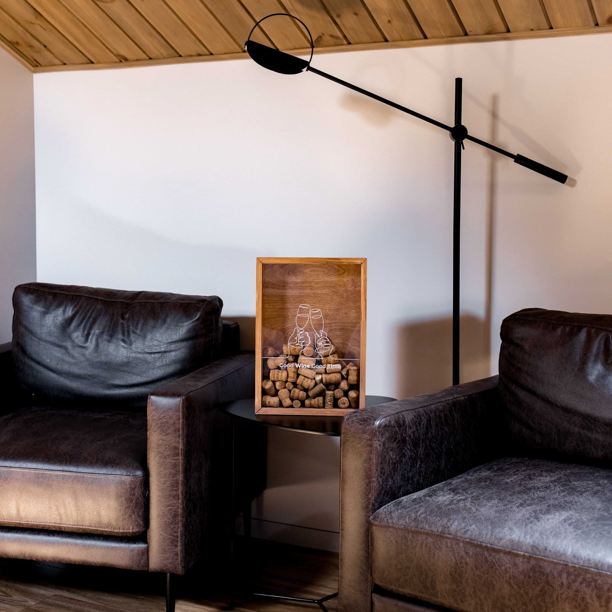 A rustic wooden framed display featuring a pair of white lace-up boots resting on a bed of brown wine corks