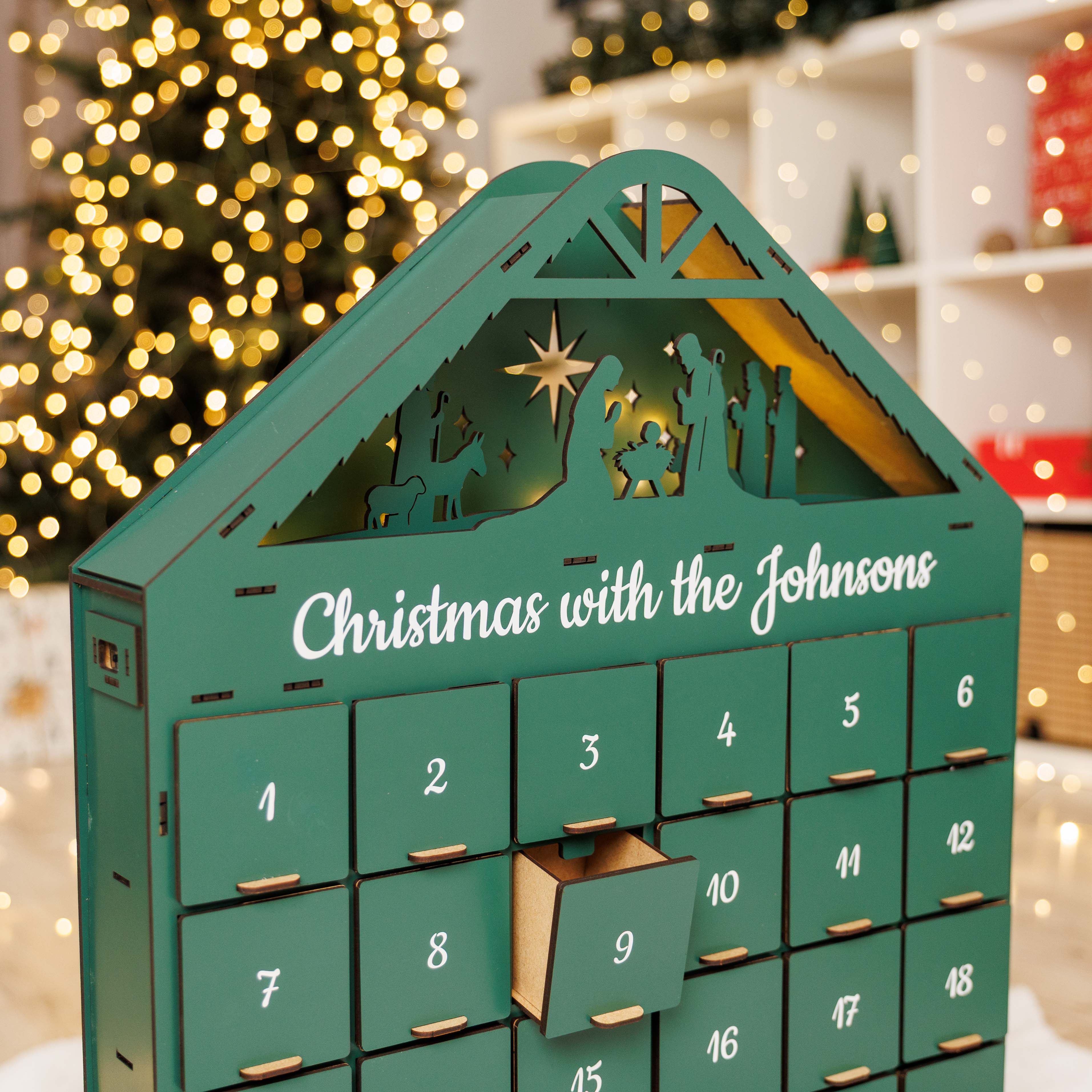 Green Advent calendar with Nativity scene design, personalized with 'Christmas with the Johnsons', against a festive background.