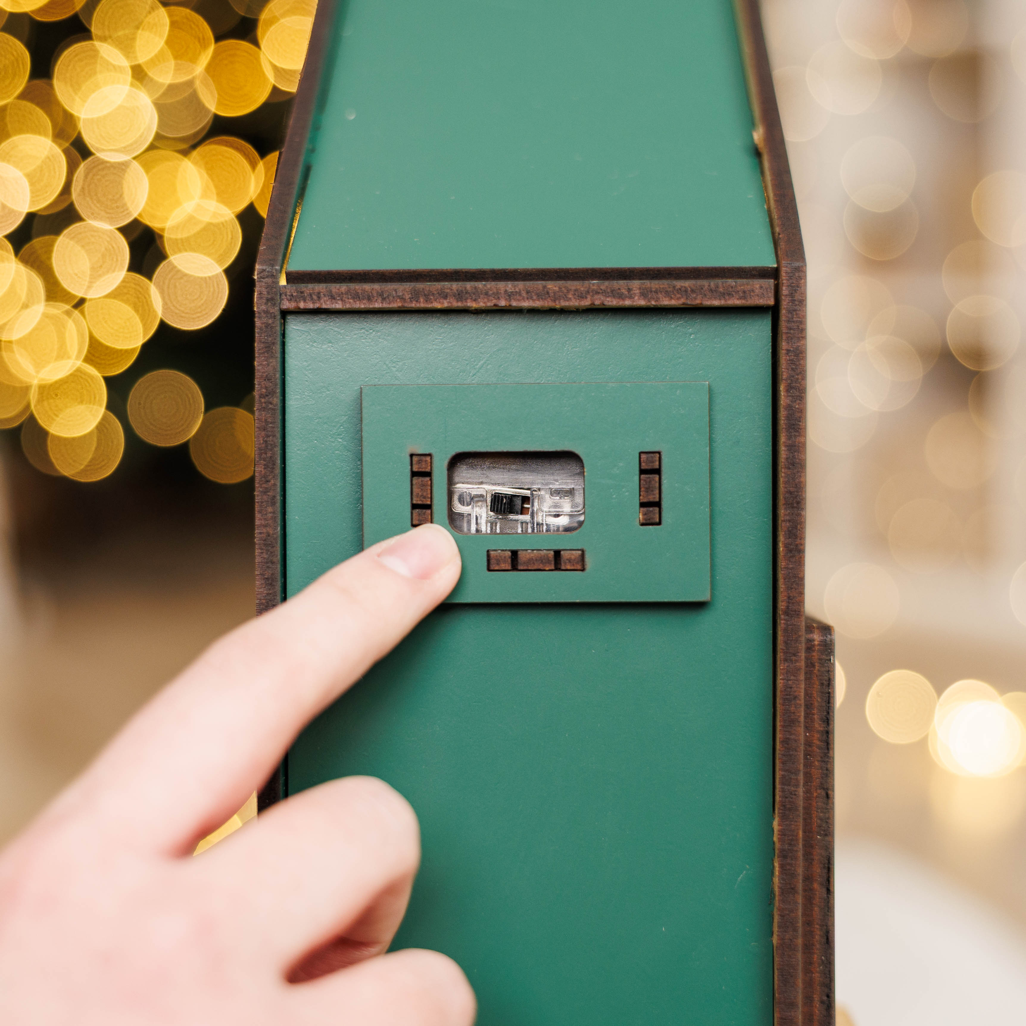 Hand pressing a button on a green door with blurred lights in the background