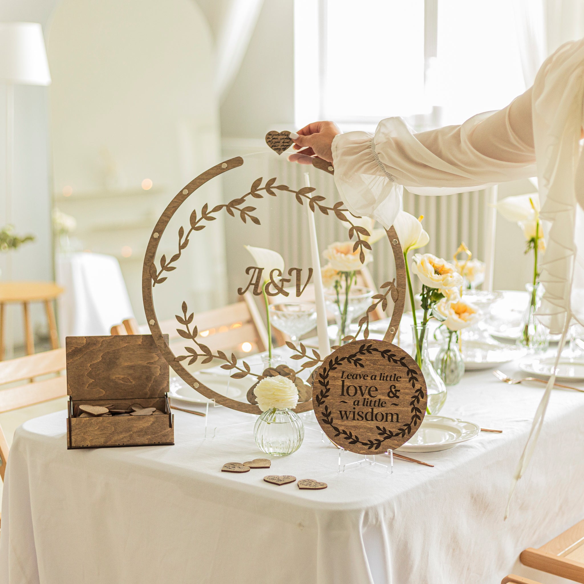 Decorative wooden sign with 'A&V' on a table setting with flowers and cards.