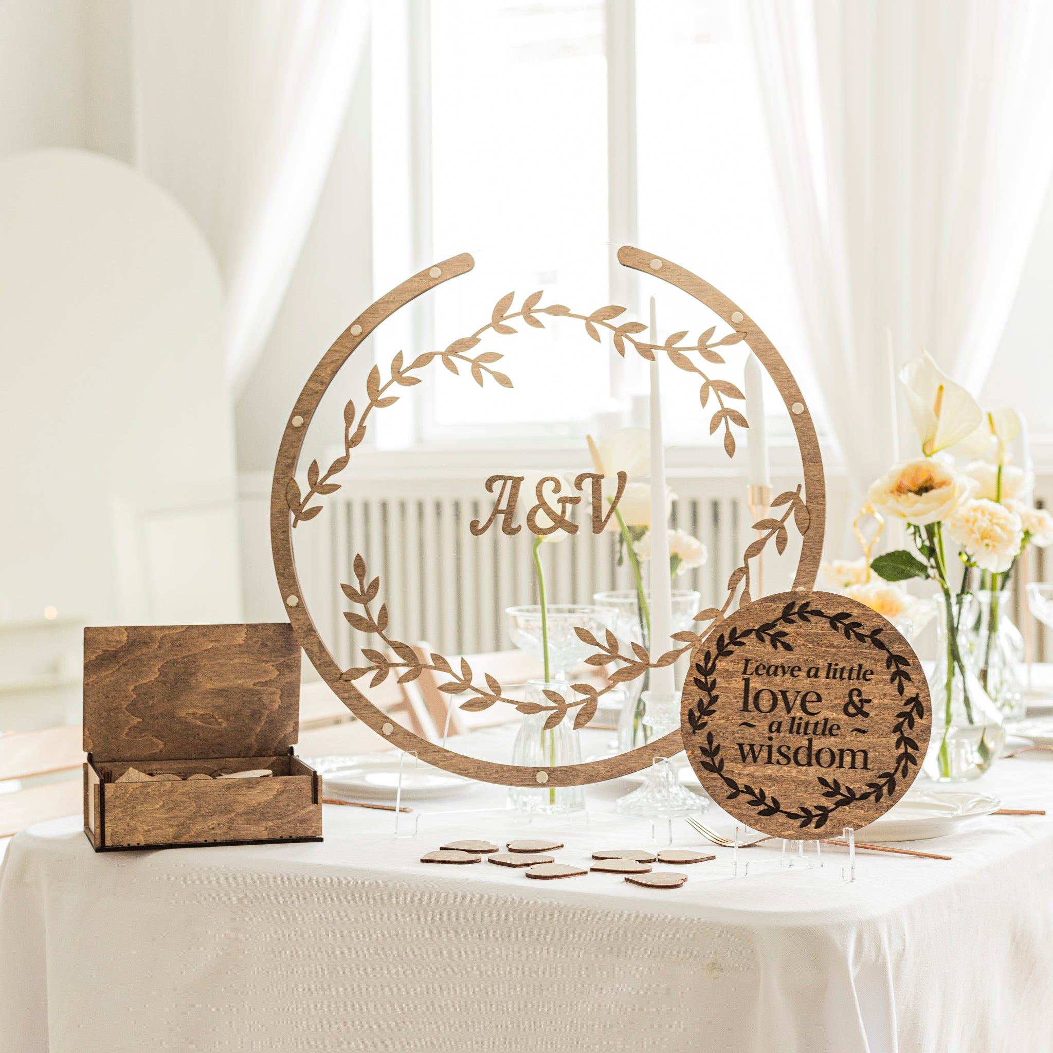 Decorative wooden signs on a table with floral arrangements and a white curtain background