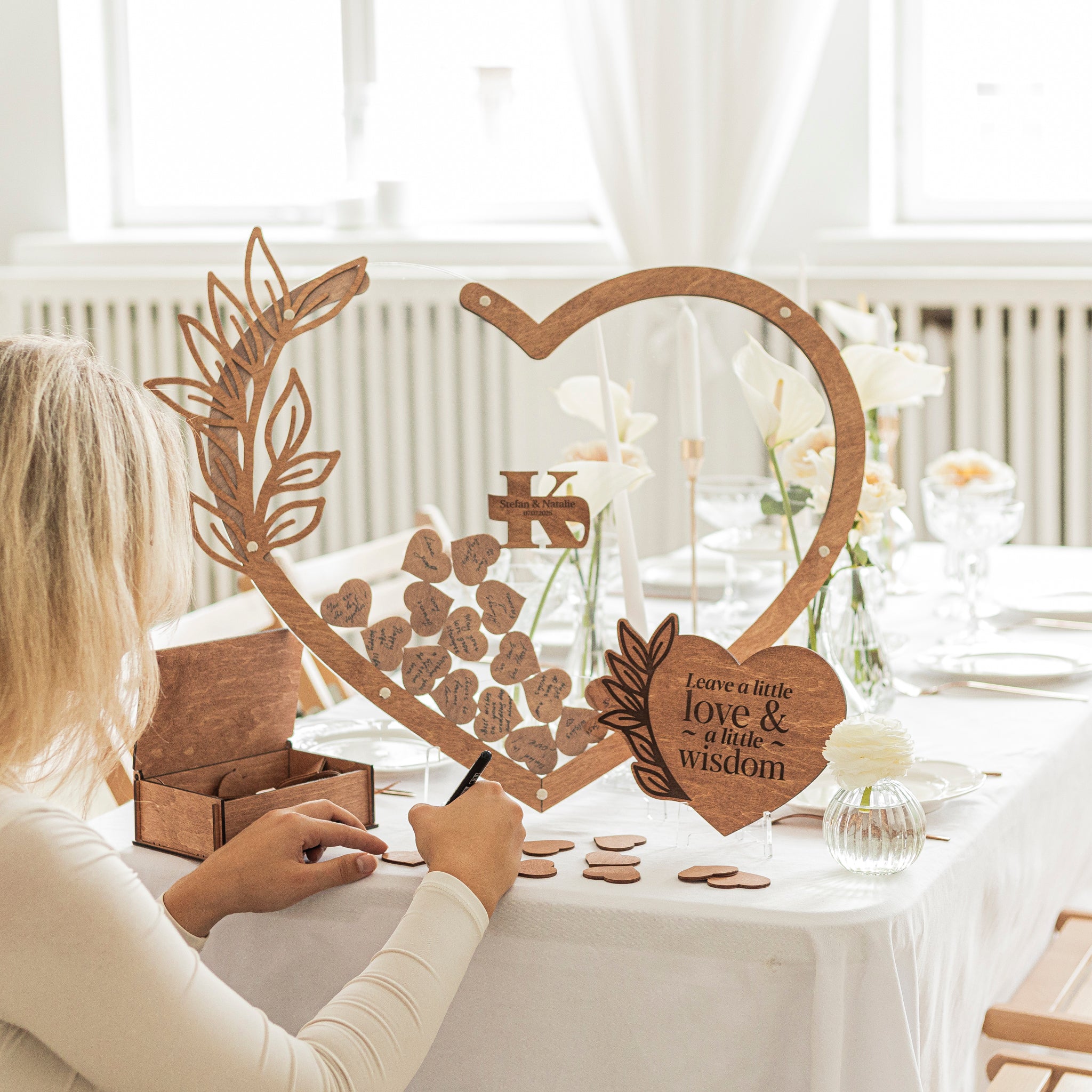Person interacting with a wooden heart-shaped decorative item on a table.