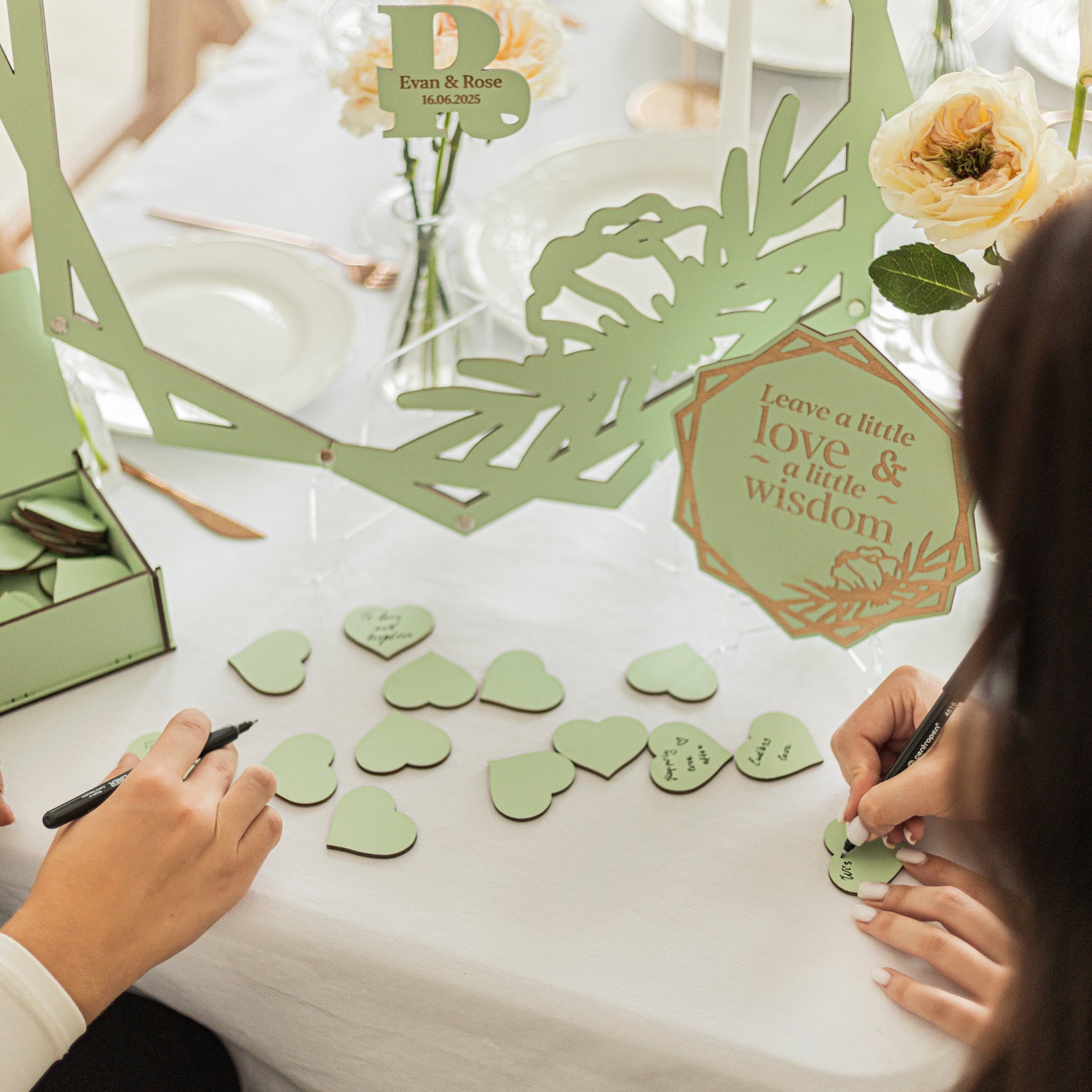 People arranging green heart-shaped cards on a table with decorative elements.