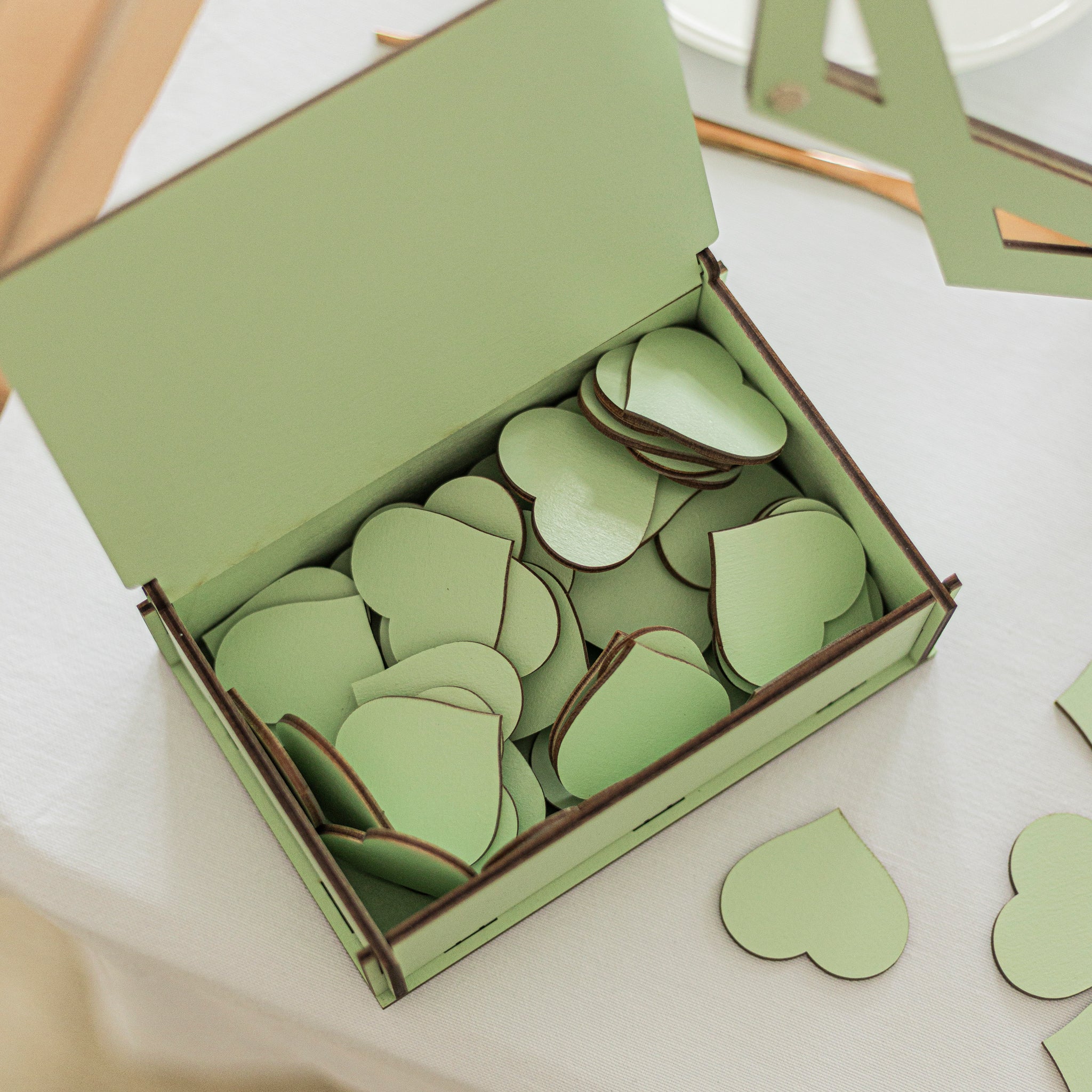 Green box filled with green heart-shaped objects on a white surface.