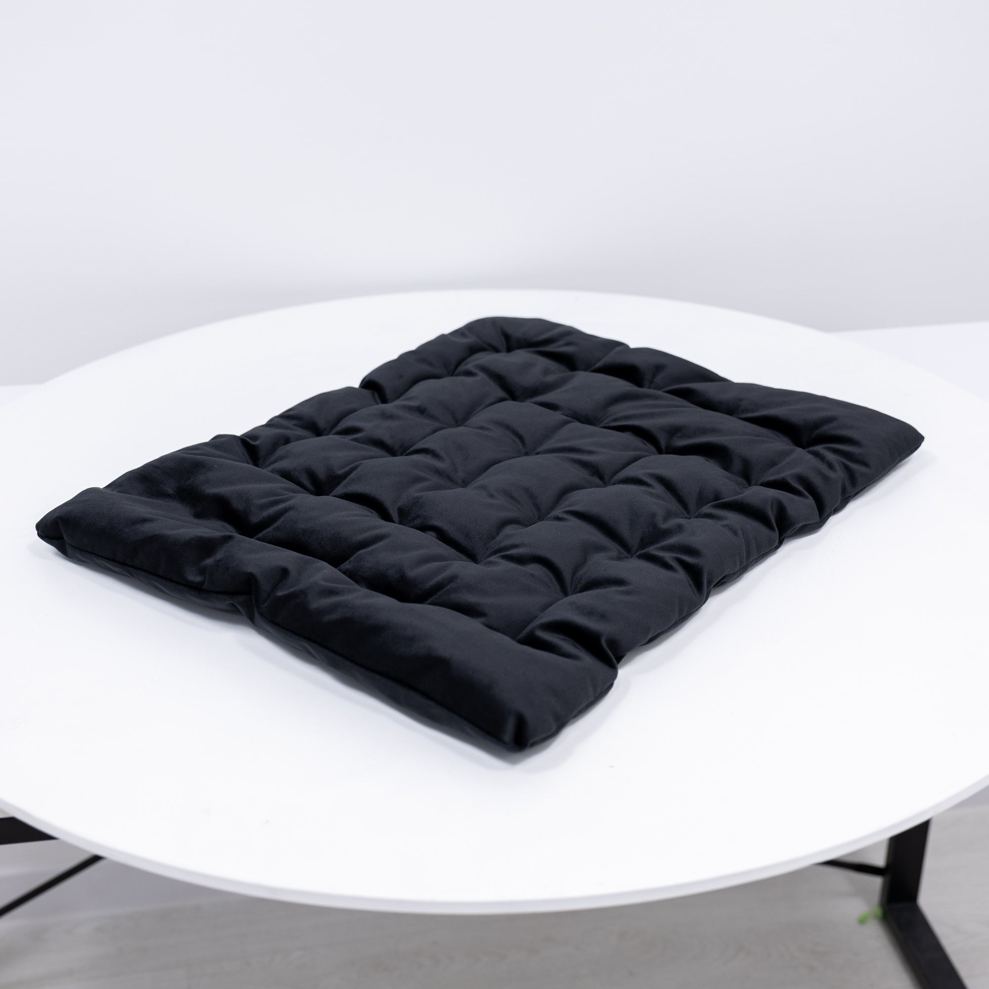 Black quilted seat pad on a white chair