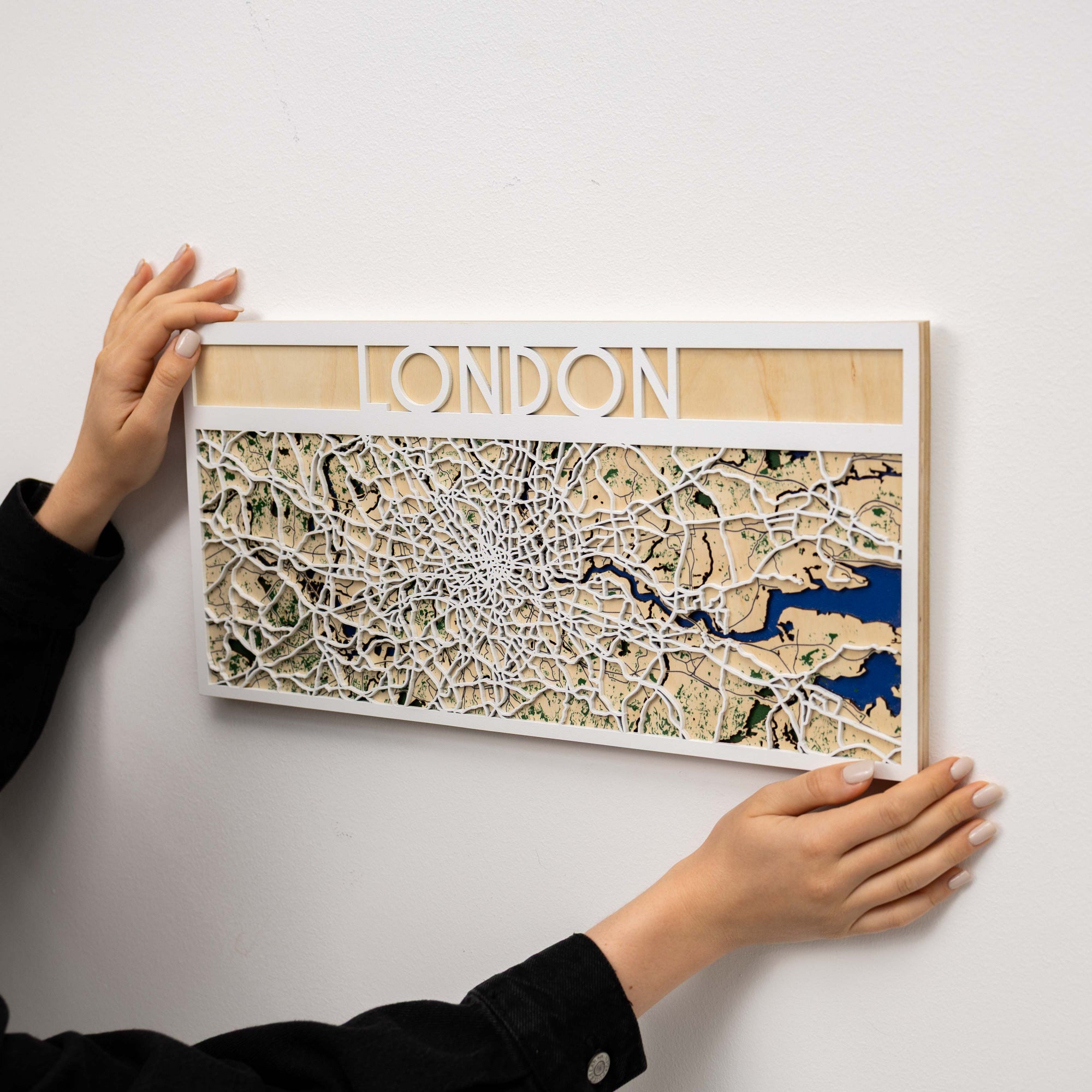 Wooden map of London held by a person on a white background