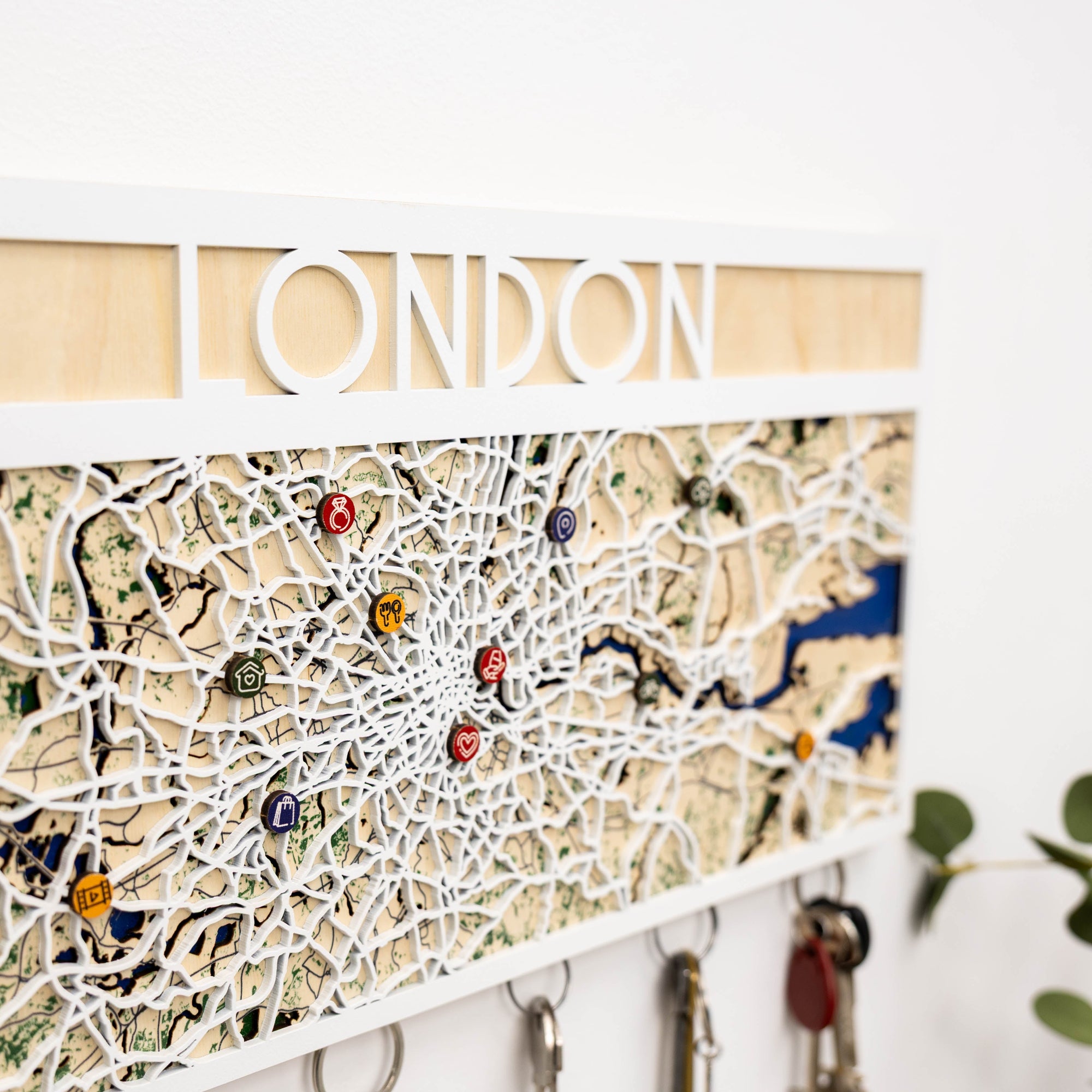 Map of London with key holders and decorative pins on a white wall.