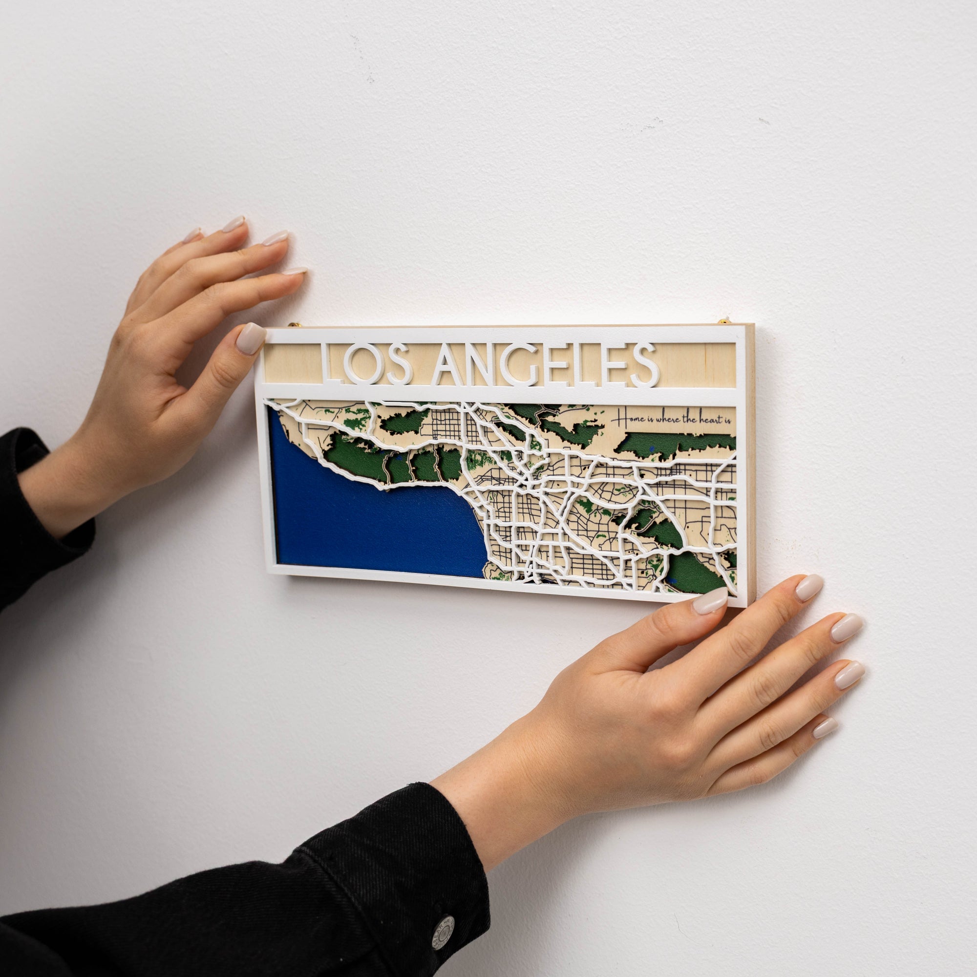 Wooden map of Los Angeles held by hands on a white background