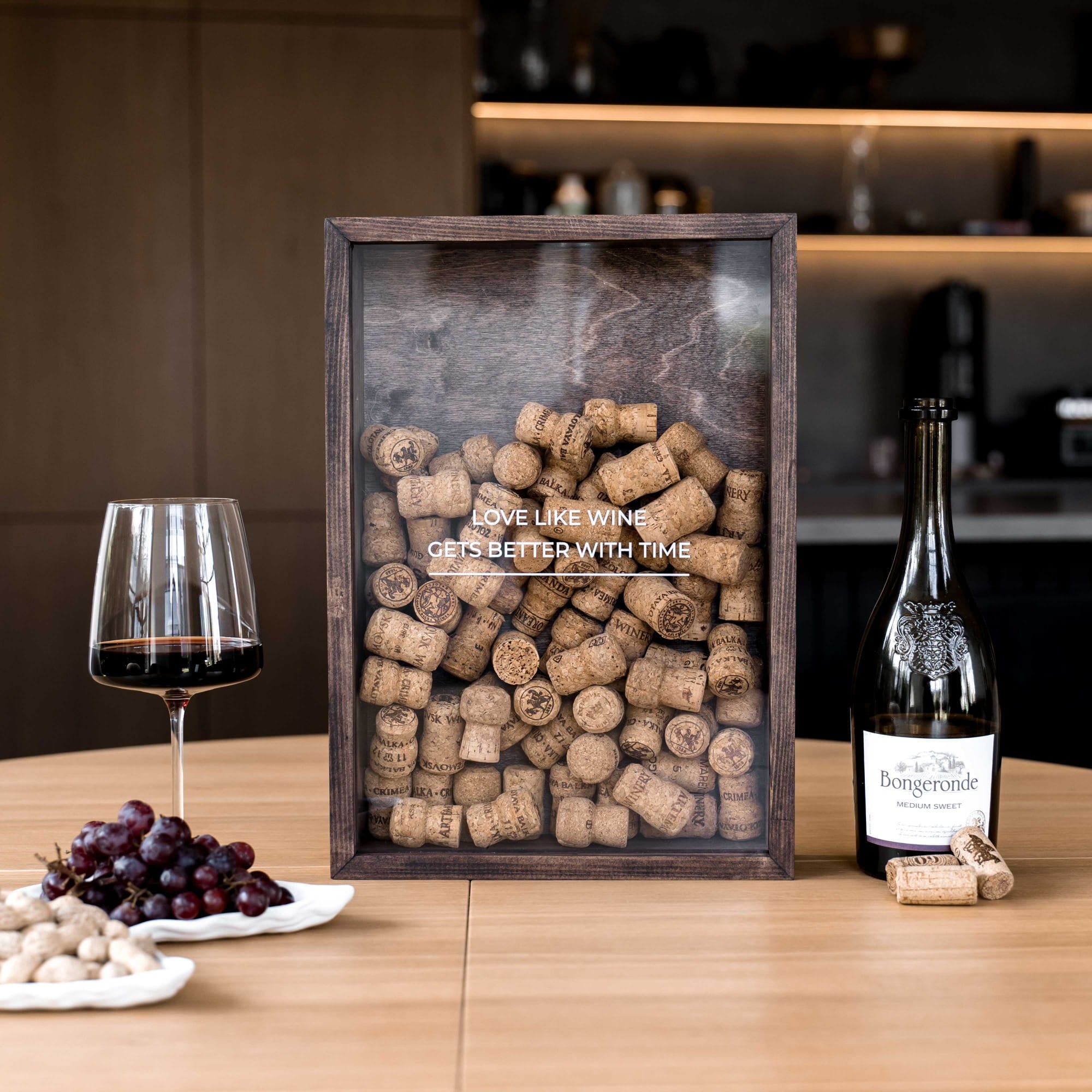 A square framed wine cork display on a wooden table