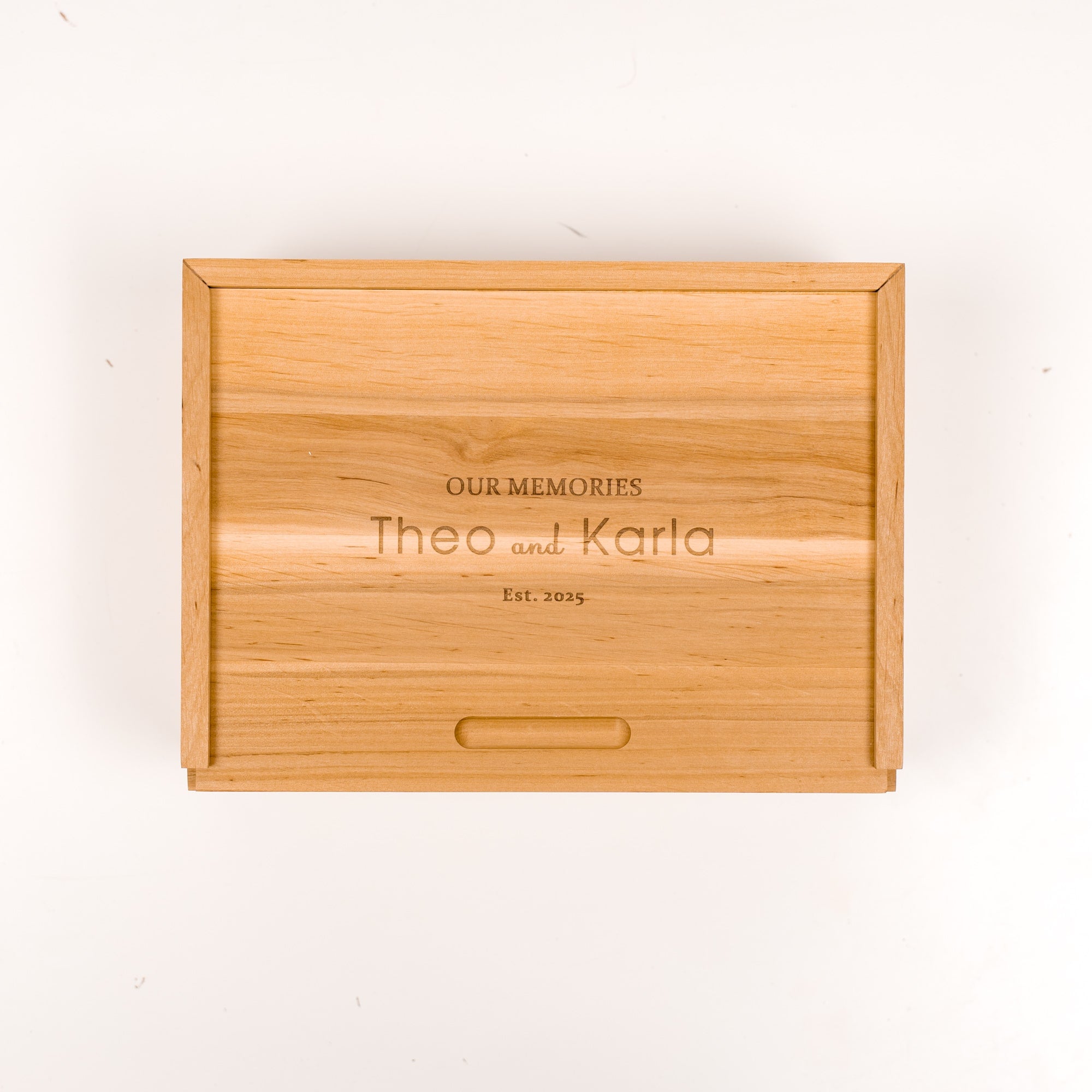 Wooden box with engraved text 'Our Memories Theo and Karla Est. 2023' on a white background