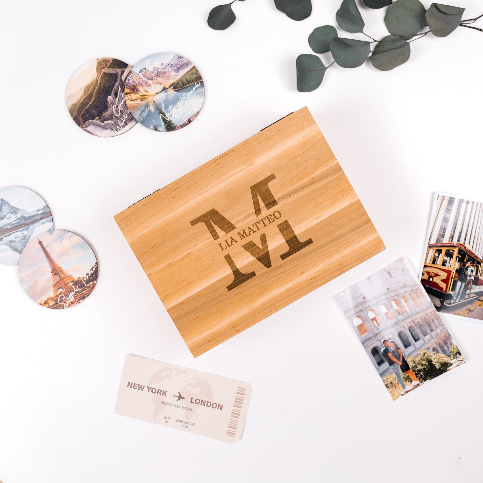 Wooden box with engraved text, travel-themed cards, and scenic photos on a white background