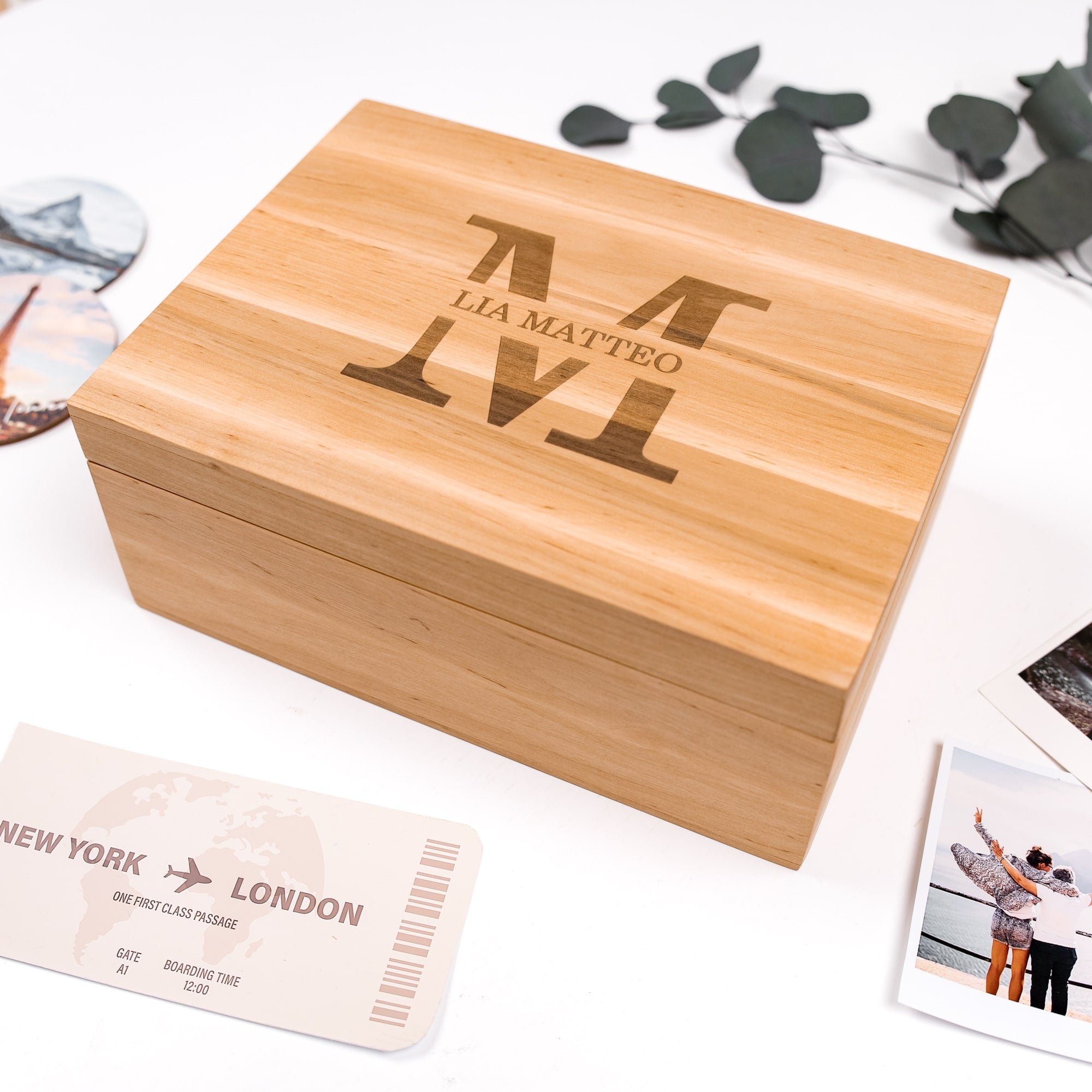 Wooden box with engraved text on a surface with travel-themed items.
