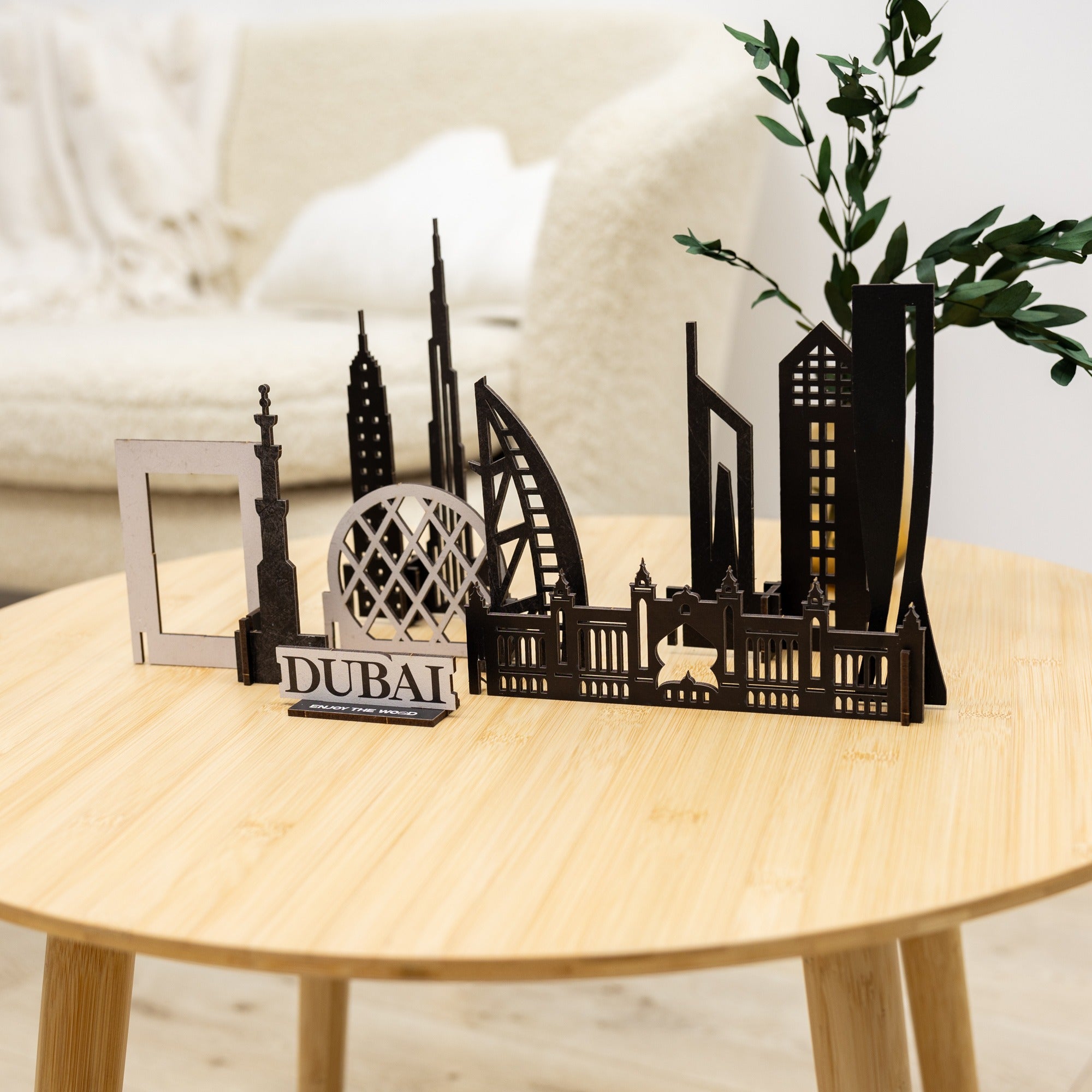Black metal model of Dubai skyline on a wooden table with a plant in the background