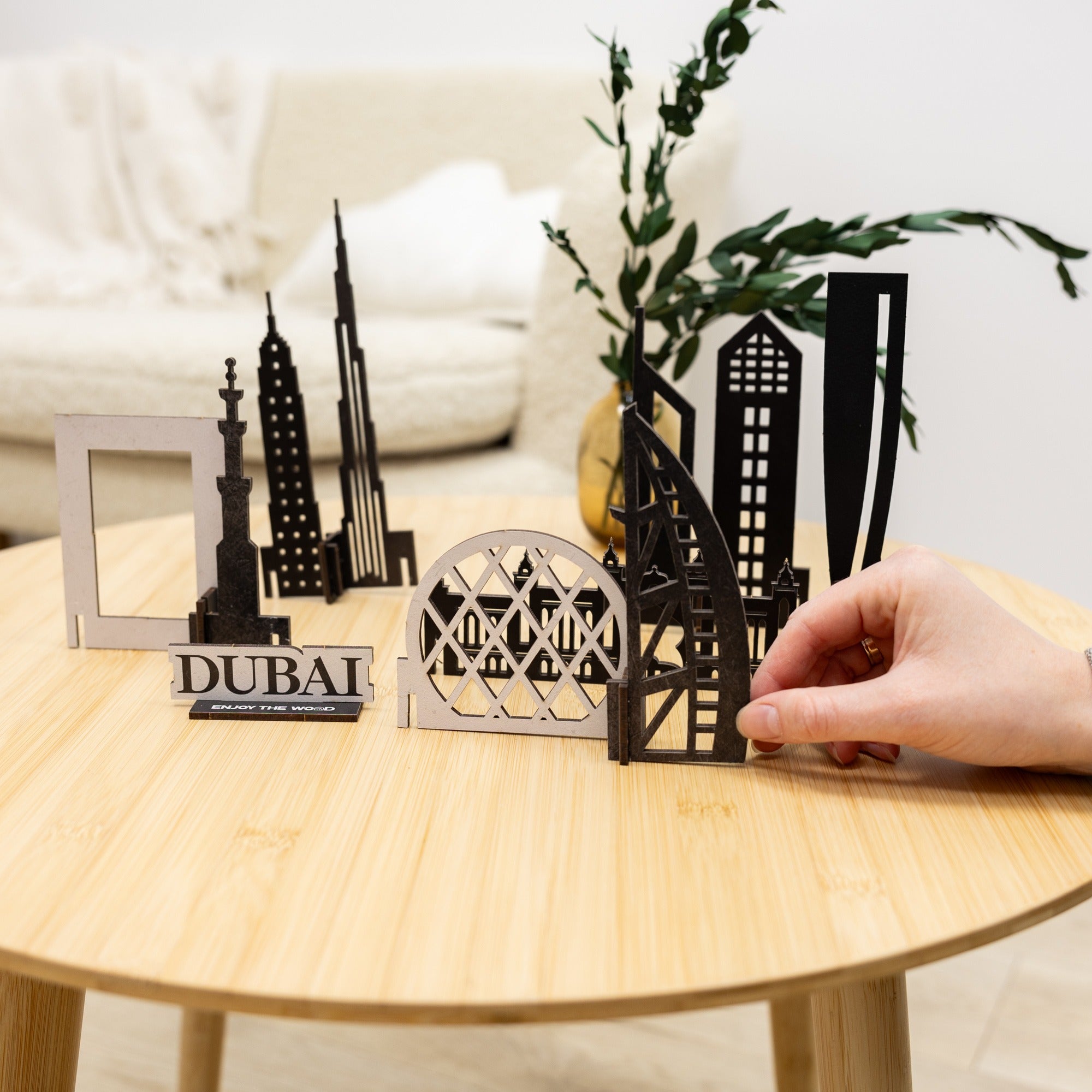 Model of Dubai skyline on a wooden table with a hand interacting with it