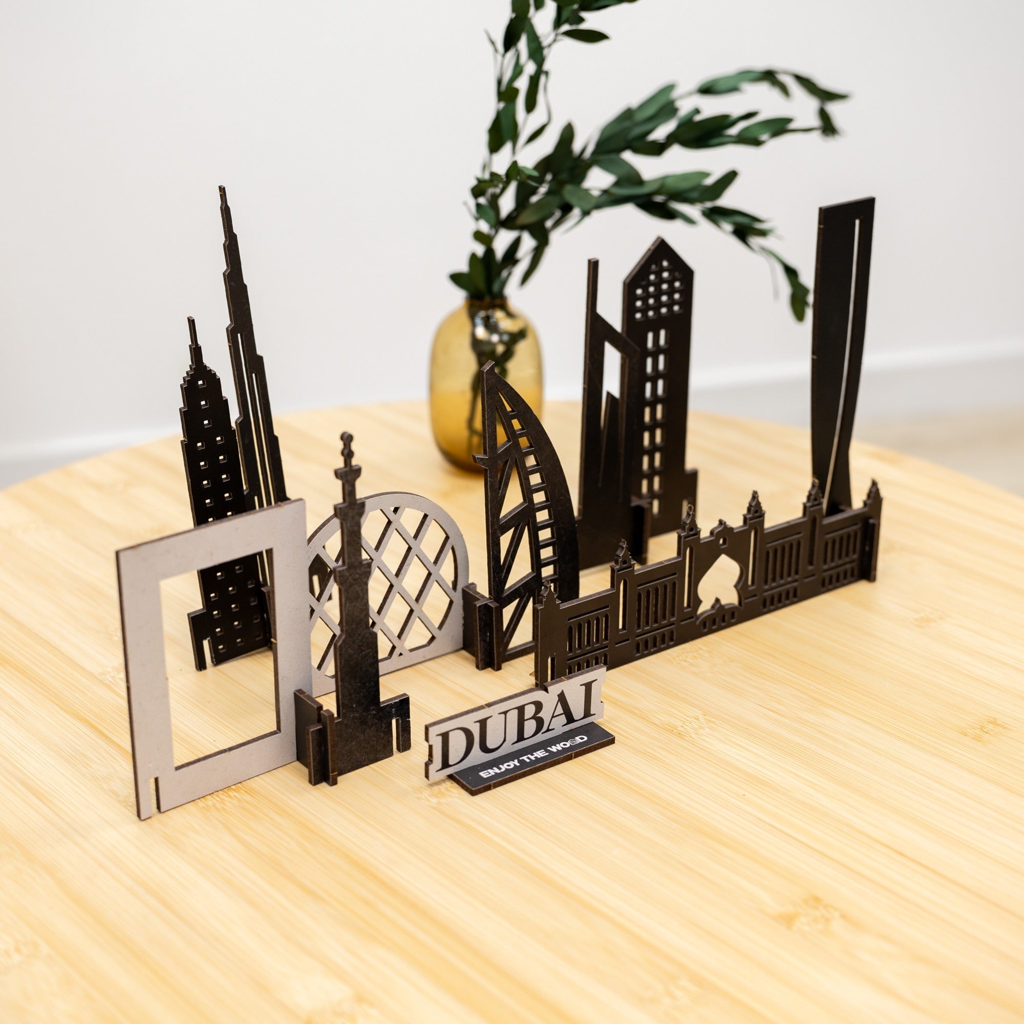 Model of Dubai skyline on a wooden surface with a plant in the background
