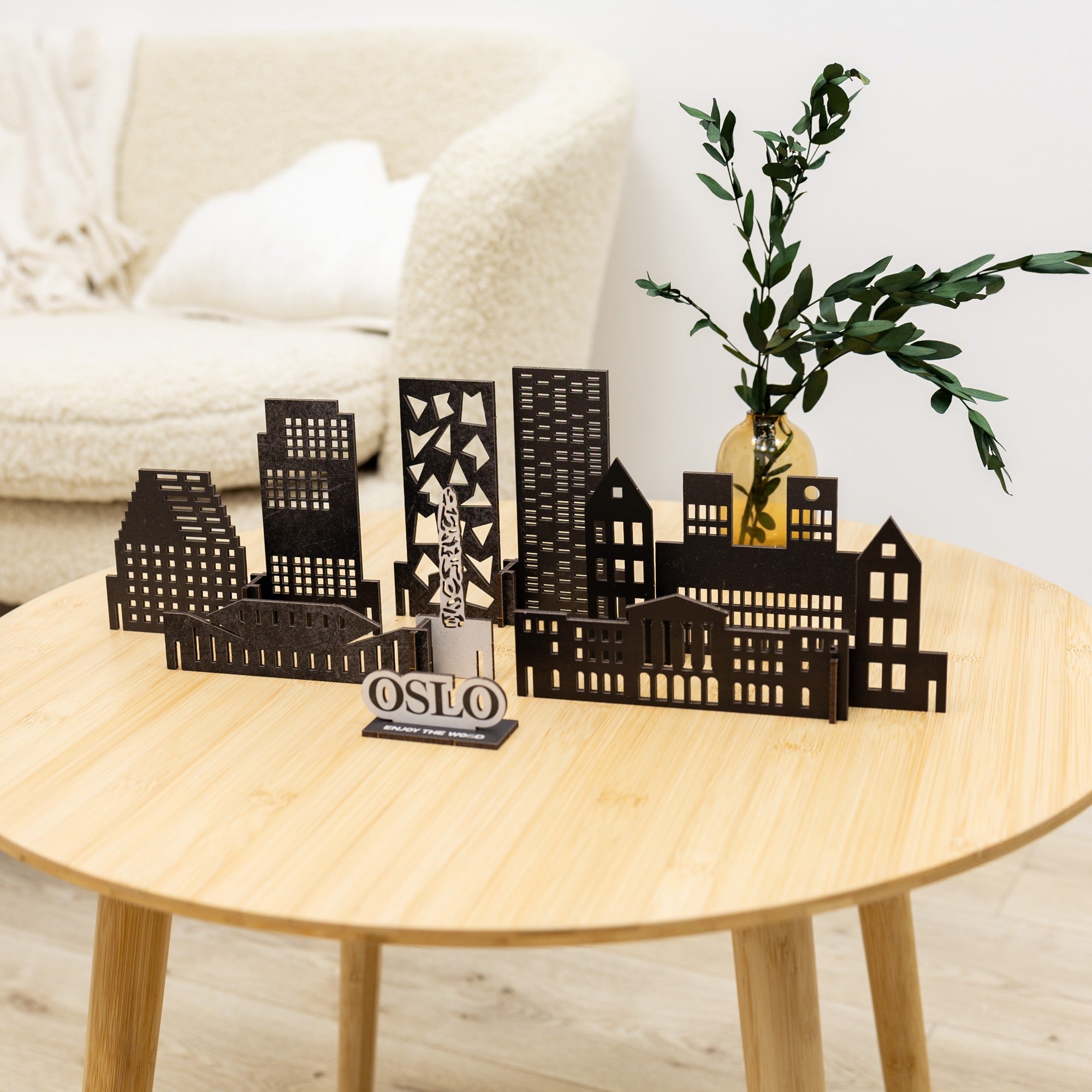 Black metal cityscape model on a wooden table with a plant in the background