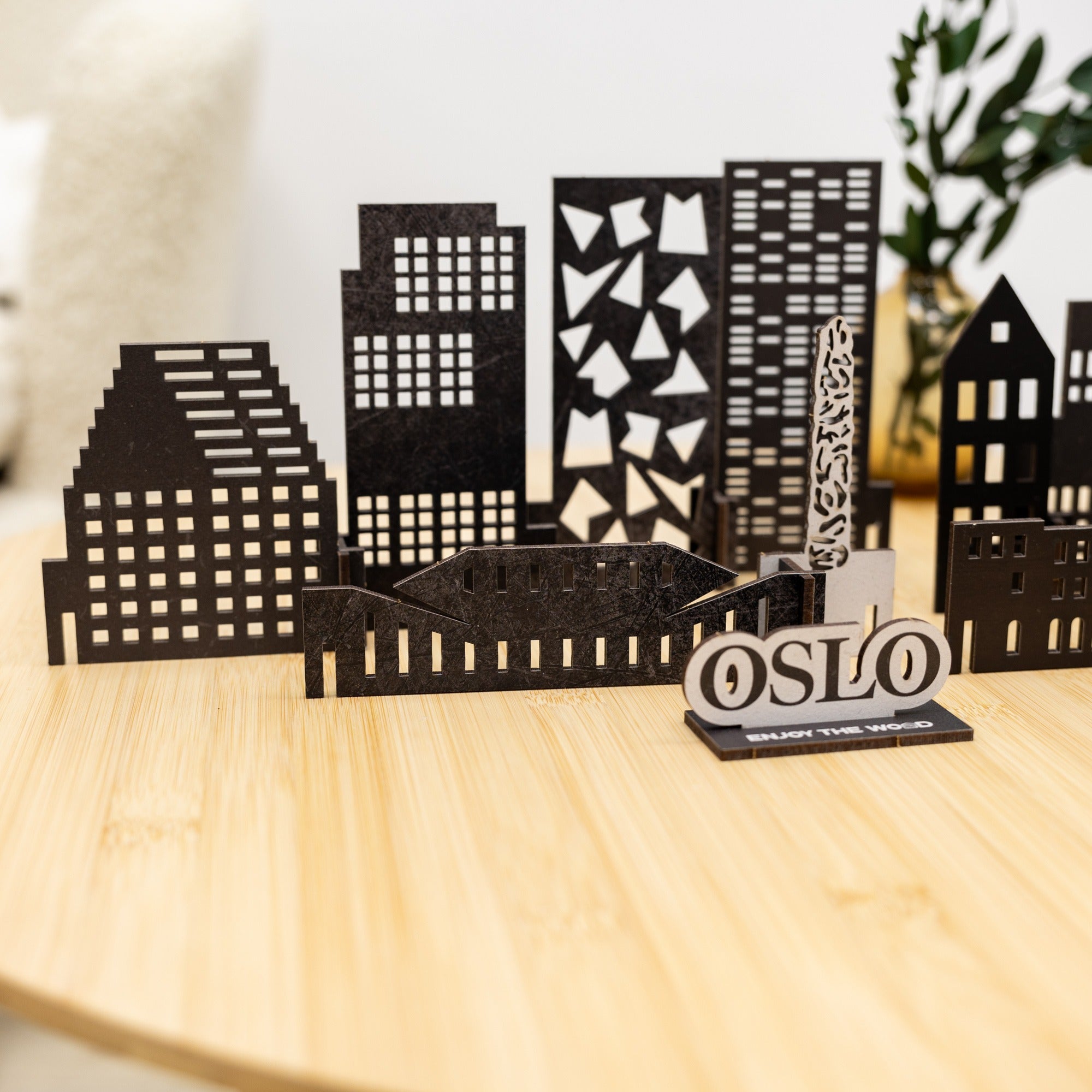 Model cityscape with buildings and 'OSLO' sign on a wooden surface