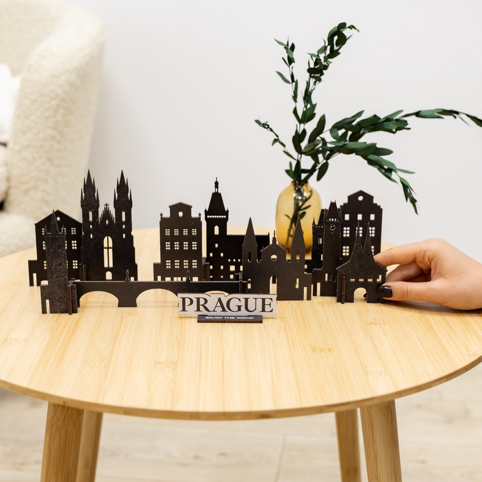 Model of Prague skyline on a wooden table with a hand holding it