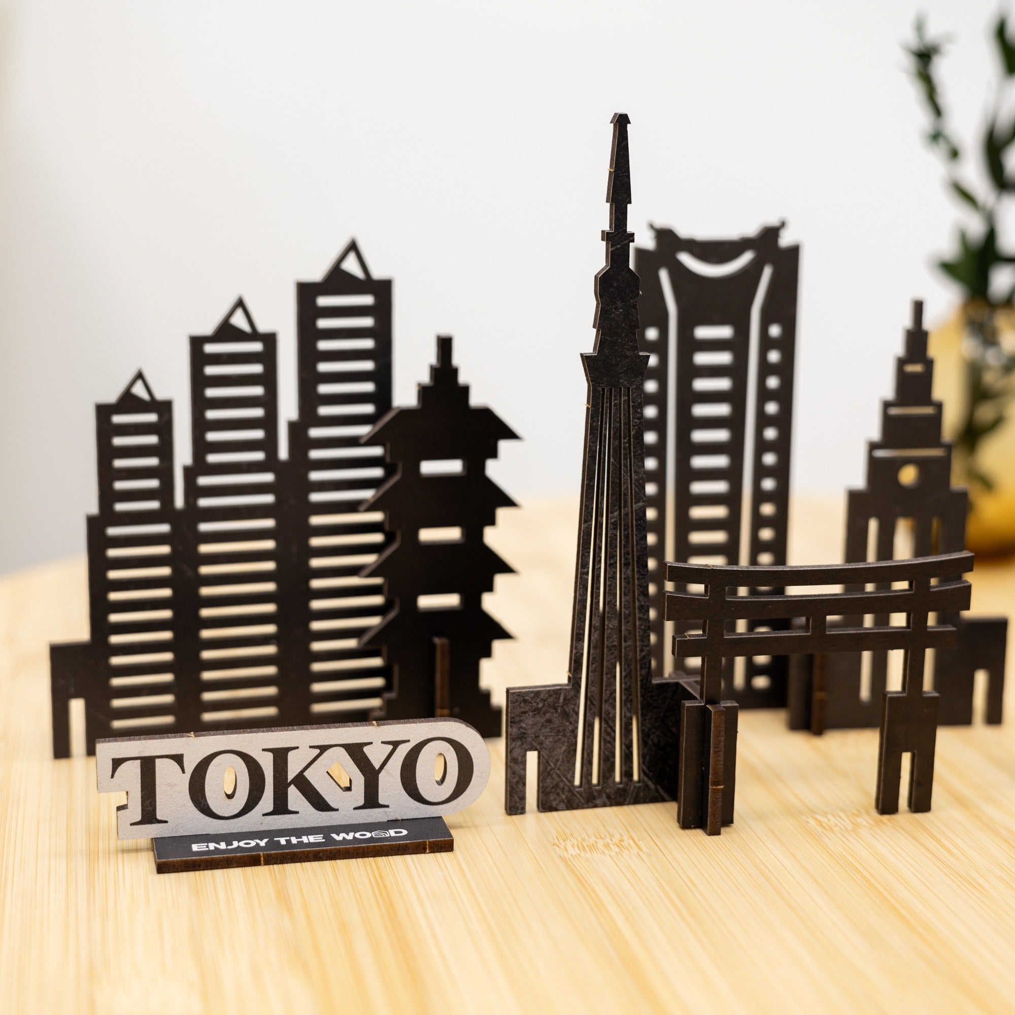 Wooden model of a city skyline with 'TOKYO' and 'ENJOY THE WOOD' text on a wooden surface.