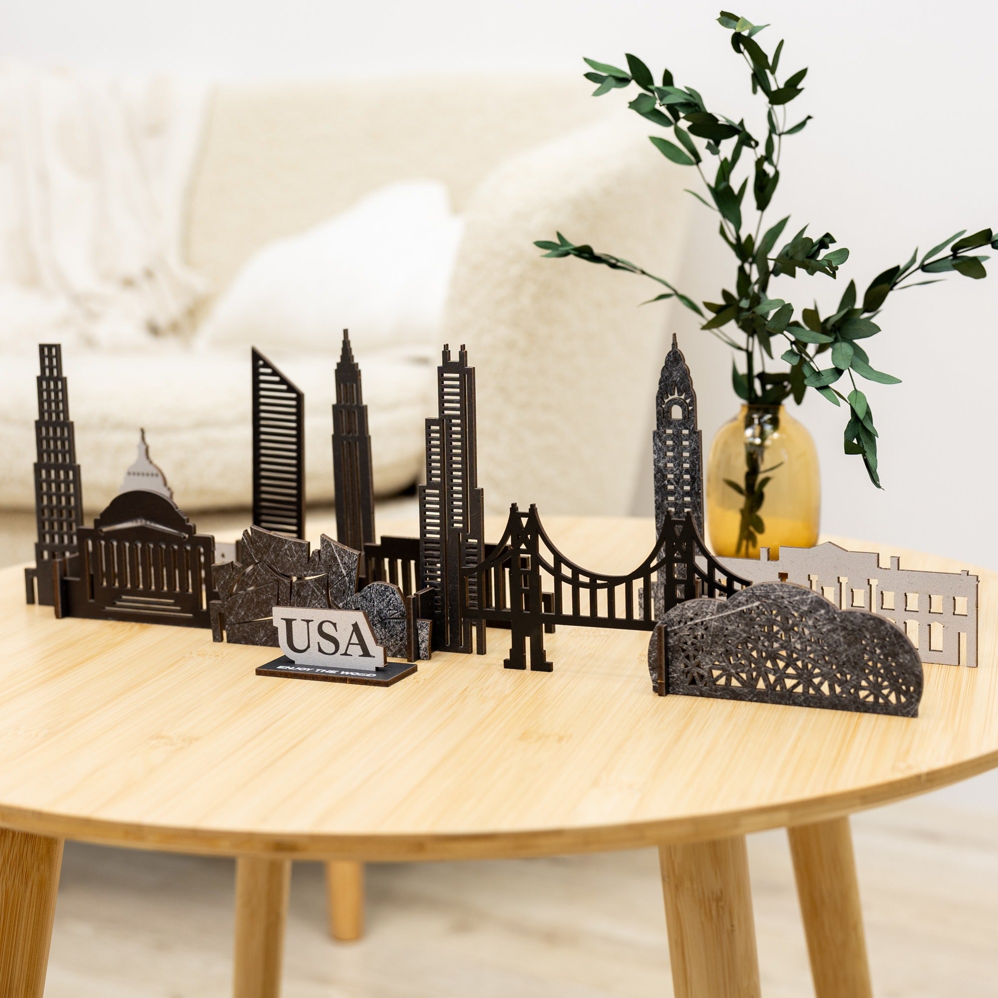 Model of a city skyline on a wooden table with a plant in the background